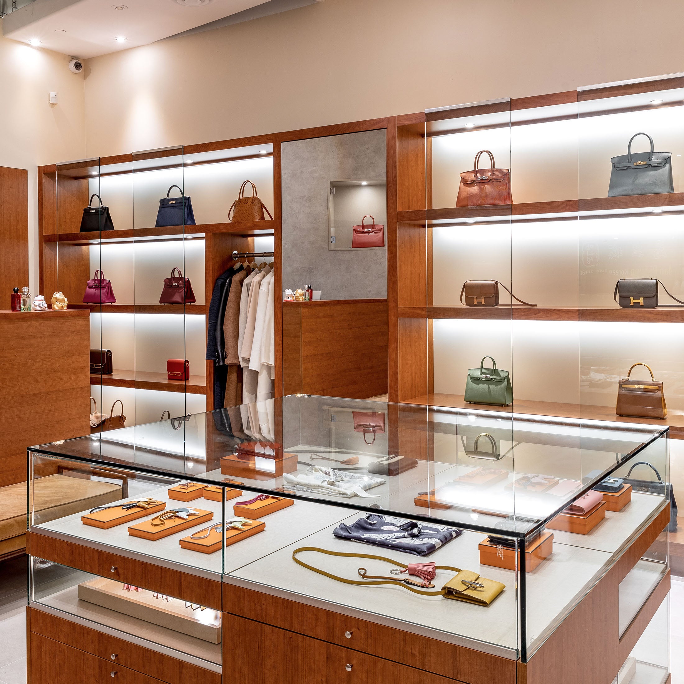 Elegant handbag showroom with illuminated wooden shelves glass cases and accessories