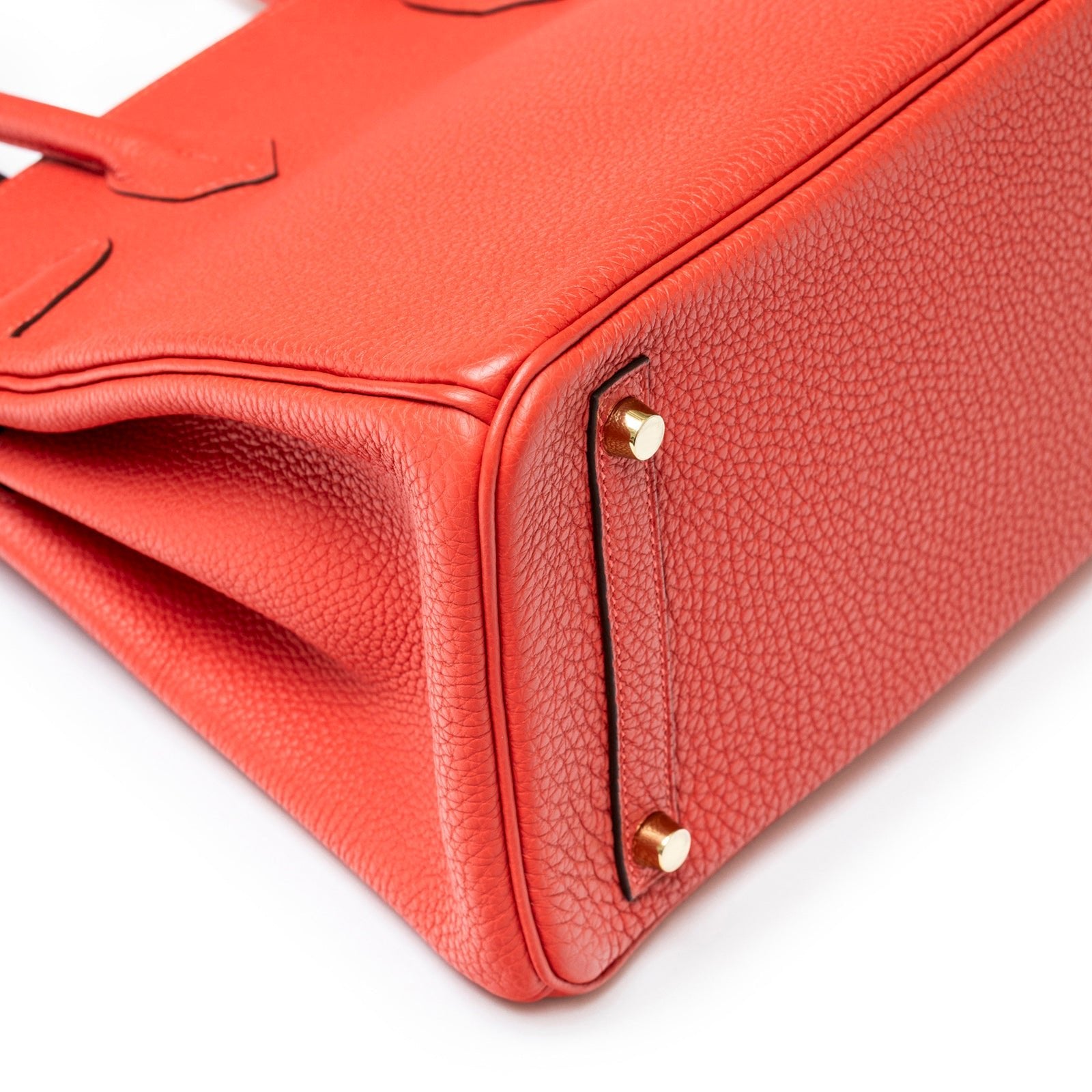 Close-up angled view of Hermès Birkin 30 Rouge Pivoine Clemence Gold Hardware bottom corner with protective feet detail