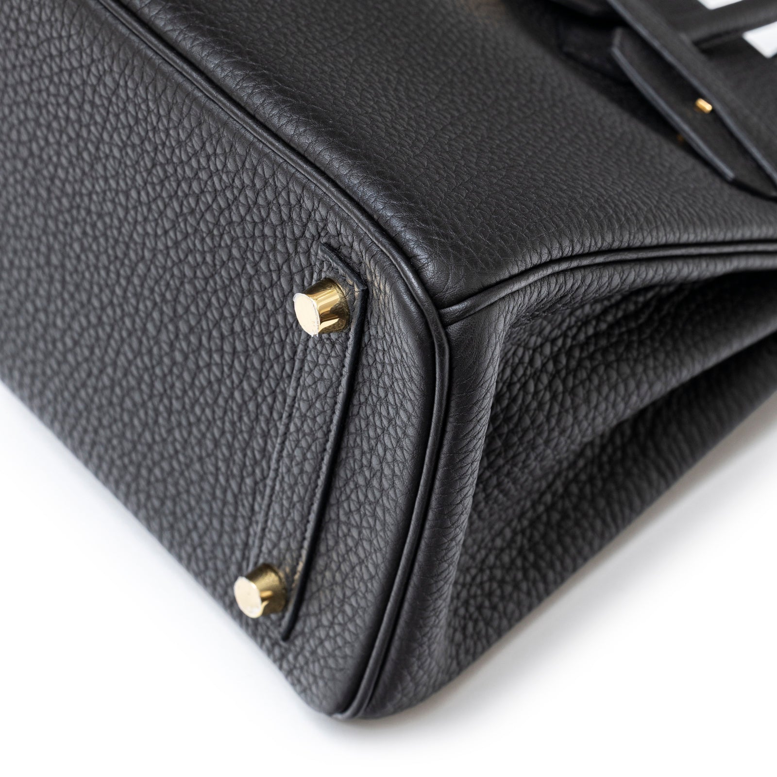 Close-up of the bottom corner of Hermès Birkin 25 Black Togo Gold Hardware showing textured leather and gold feet detail