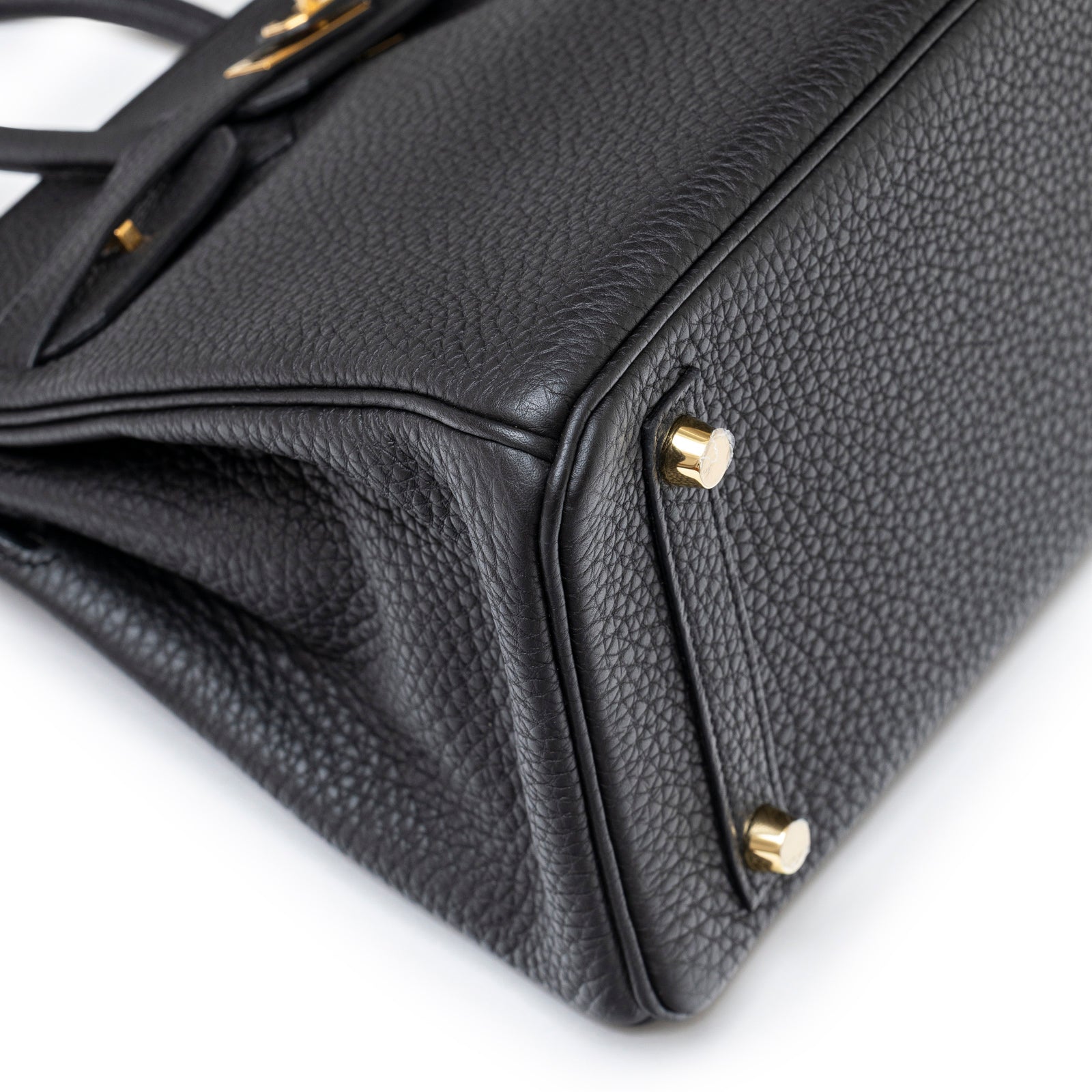 Close-up angled shot of Hermès Birkin 25 Black Togo Gold Hardware showing textured leather and gold feet details