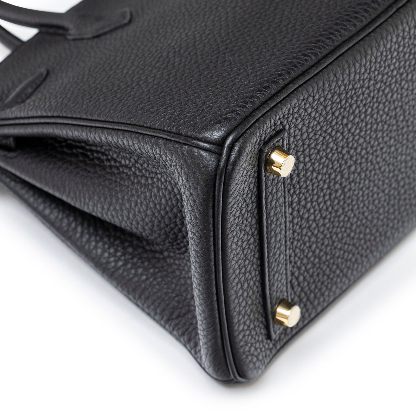 Close-up angled shot of Hermès Birkin 25 Black Togo Gold Hardware showing textured leather and gold feet details