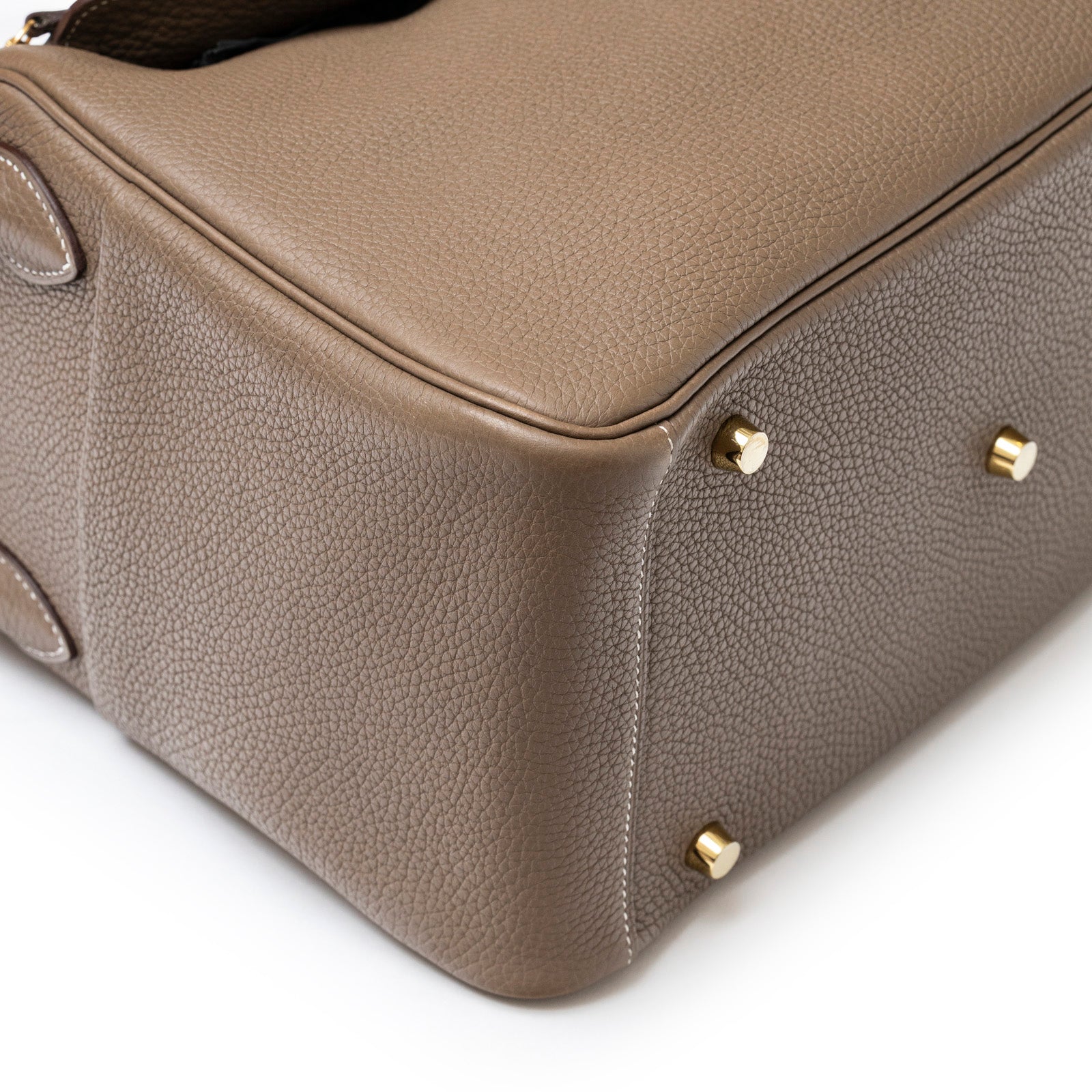 Close-up of bottom corner and gold feet on Hermès Lindy 30 Etoupe Clemence Gold Hardware handbag