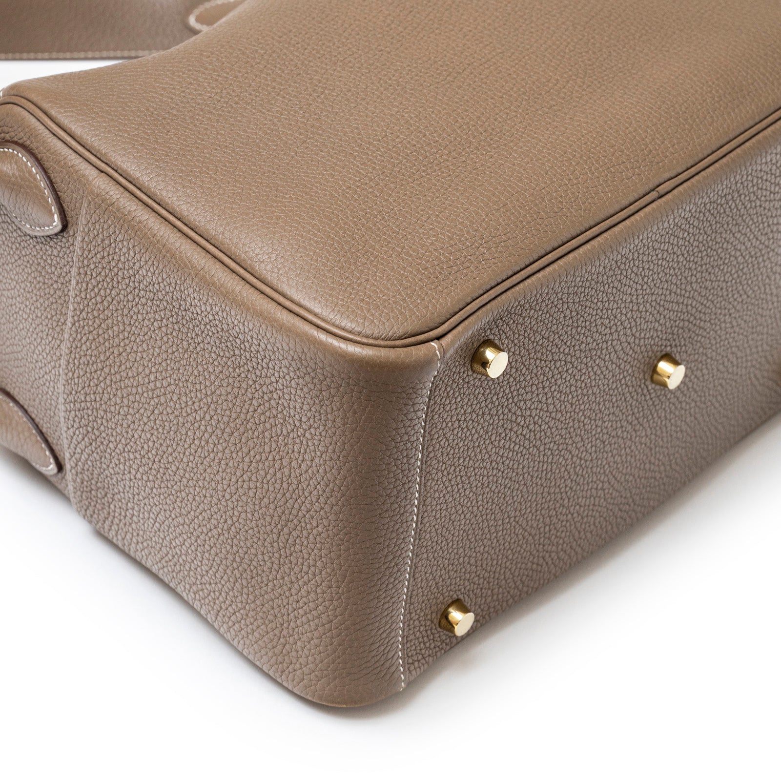 Close-up bottom view of Hermès Lindy 30 Etoupe Clemence Gold Hardware leather with gold feet detailing