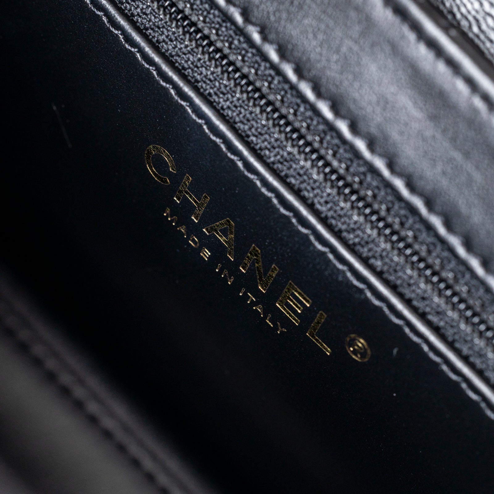 Close-up interior view of Chanel Mini Kelly Shopper Black Shiny Aged Calfskin Brushed Gold Hardware logo and stitching detail
