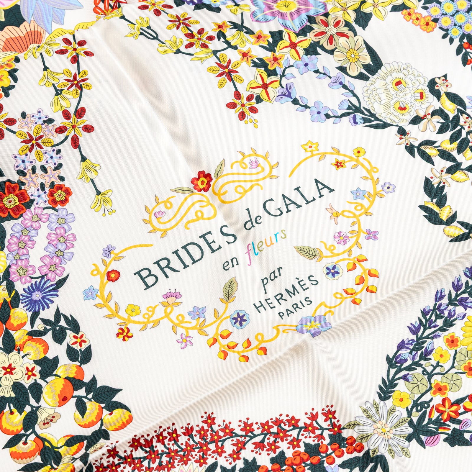 Close-up of floral print and logo on Hermès Brides de Gala en Fleurs Scarf 90 Su/Black/Ivory/Multi silk fabric