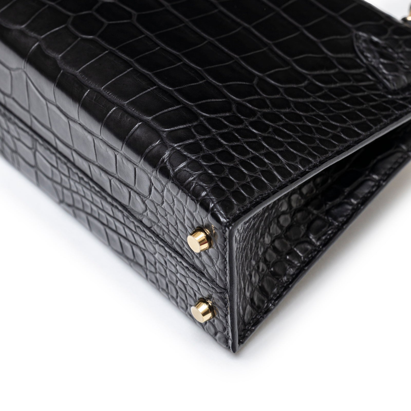 Close-up of bottom corner showing black matte alligator texture and permabrass hardware on Hermès Horseshoe Mini Kelly II Black/Blue Matte Alligator Permabrass Hardware