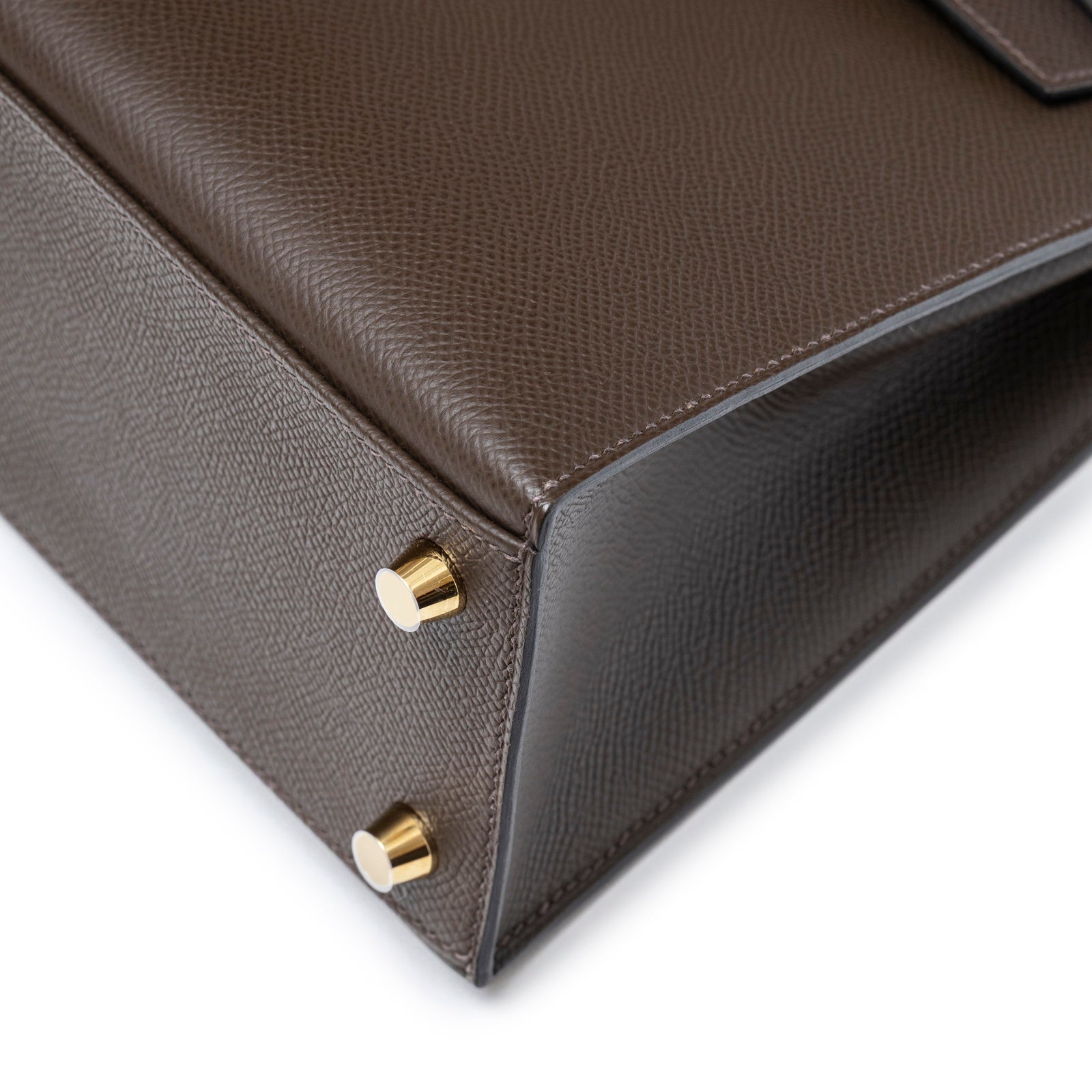 Close-up angled shot of bottom corner and gold hardware feet on Hermès Kelly 25 Sellier Ecore Epsom Gold Hardware bag