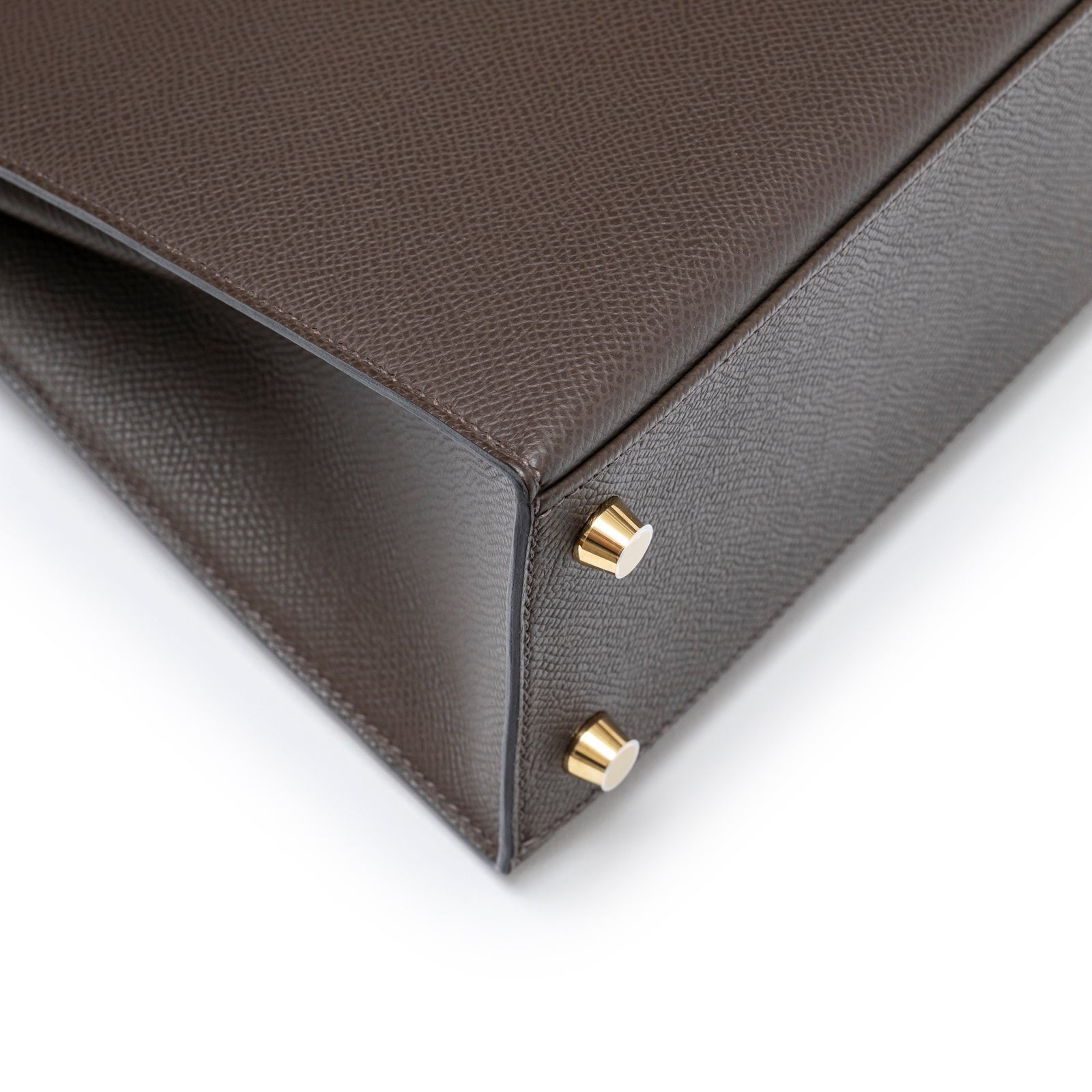 Close-up bottom corner view of Hermès Kelly 25 Sellier Ecore Epsom Gold Hardware with protective feet detail