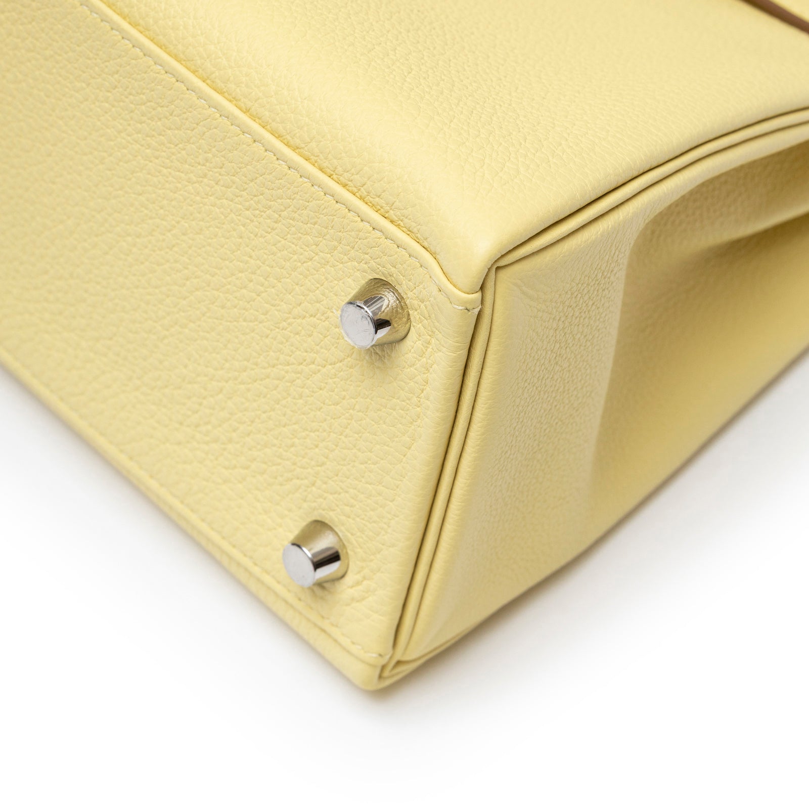 Close-up of bottom corner on Hermès Kelly 25 Retourne Togo Jaune Poussin Palladium Hardware showing leather texture and metal feet
