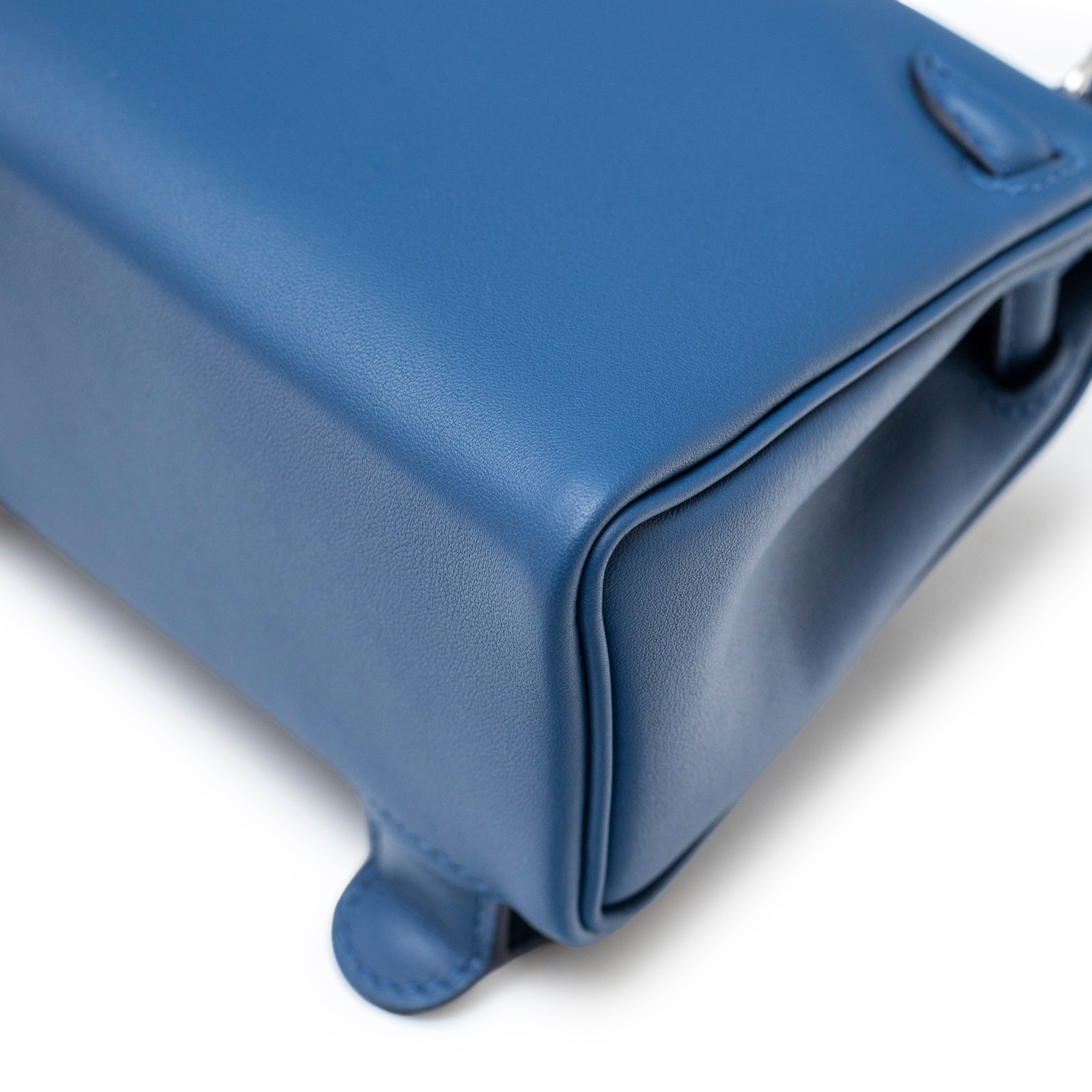 Close-up of bottom corner and smooth leather detail on Hermès Quelle Idolle Kelly Doll Bleu Tie and Caban Swift Palladium Hardware bag