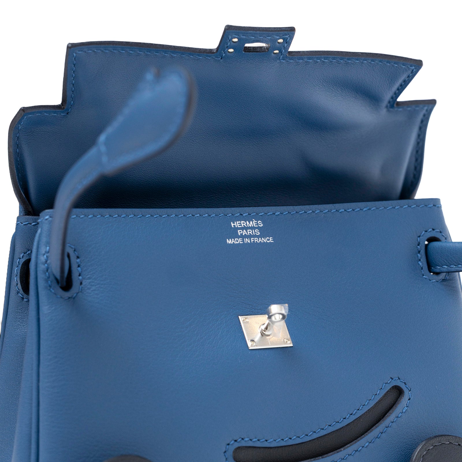 Close-up interior view of Hermès Quelle Idolle Kelly Doll Bleu Tie and Caban Swift Palladium Hardware showing logo and clasp detail