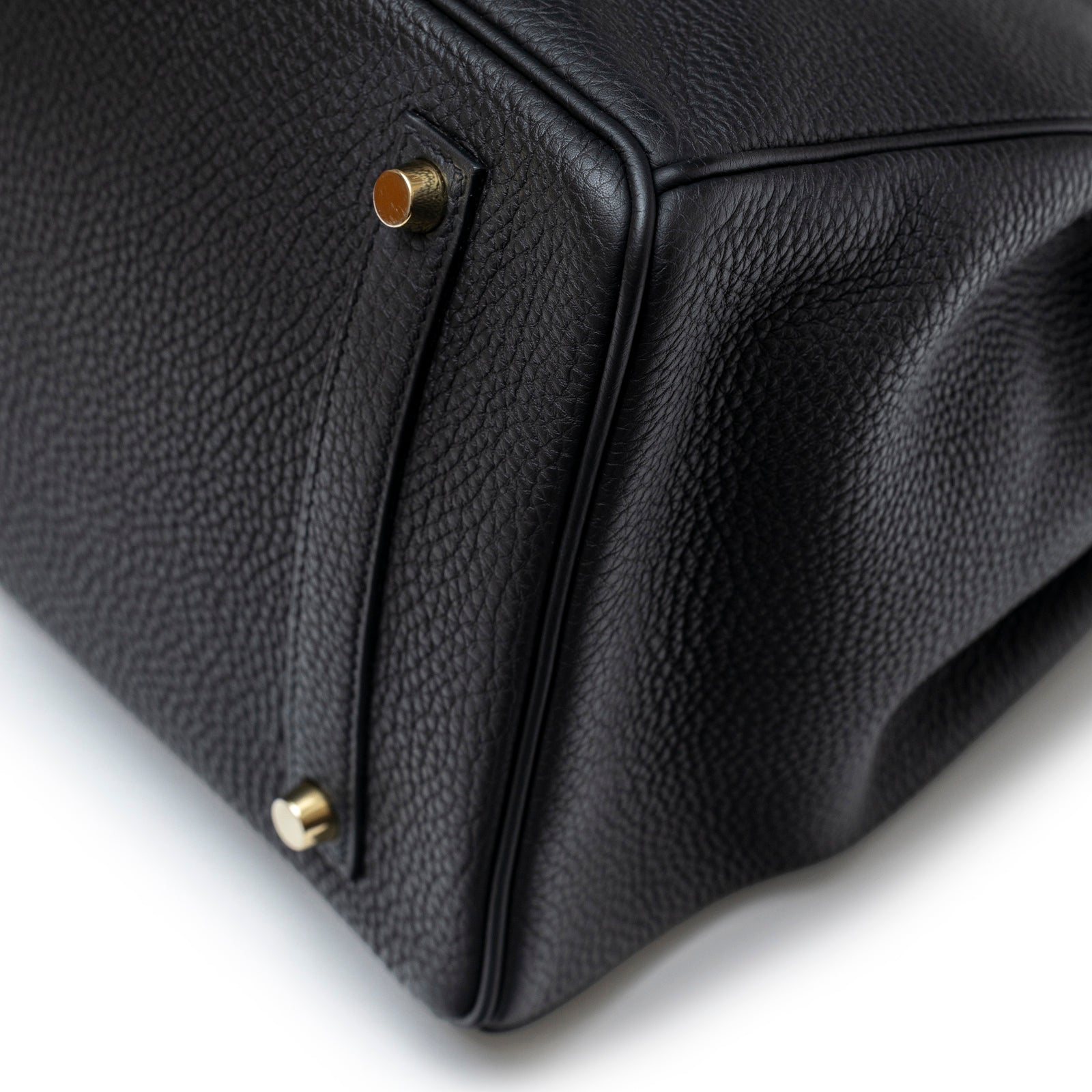 Close-up of bottom corner on Hermès Birkin 35 Black Togo Gold Hardware showing textured leather and gold feet detail
