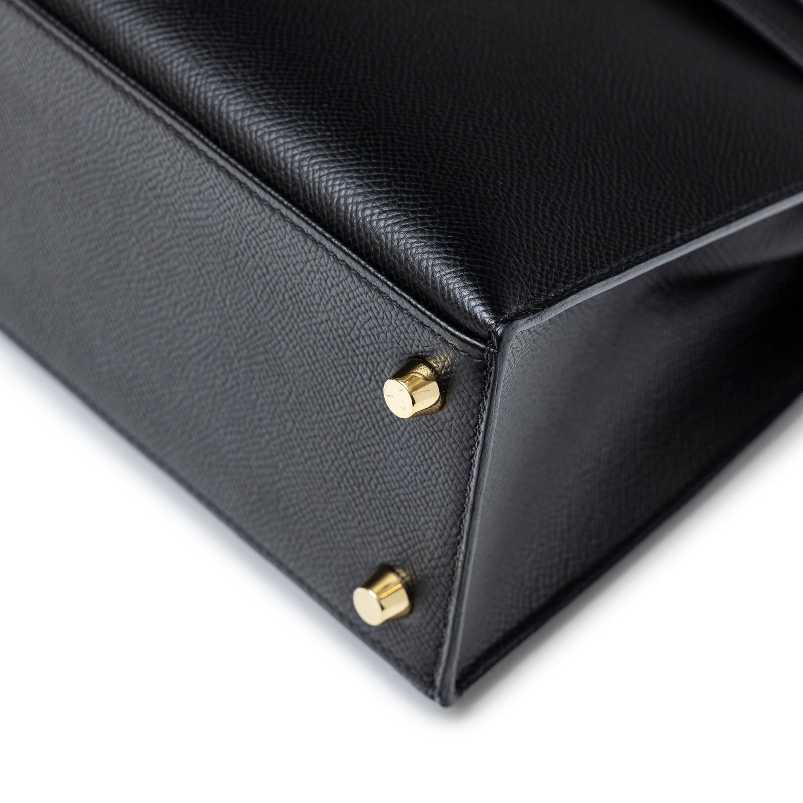 Close-up of bottom corner and gold hardware feet on Hermès Kelly Sellier 25 Black Epsom Gold Hardware bag