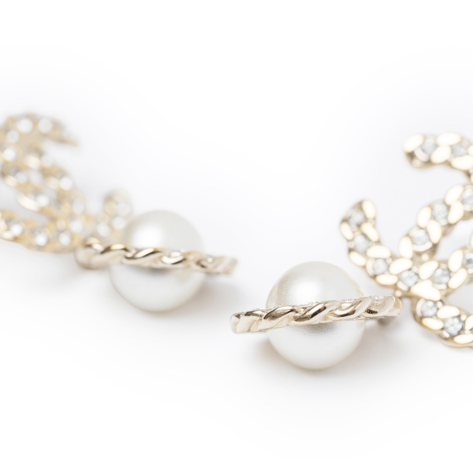 Close-up of twisted light gold detail and pearl on Chanel Crystal Pearl/Light Gold CC Drop Earring pair