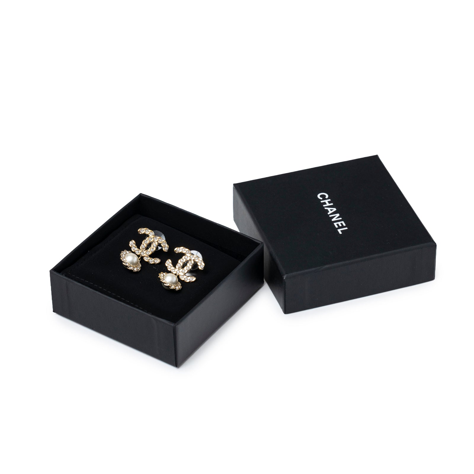 Angled view of Chanel Crystal Pearl/Light Gold CC Drop Earring in black box with lid beside showing pearl details