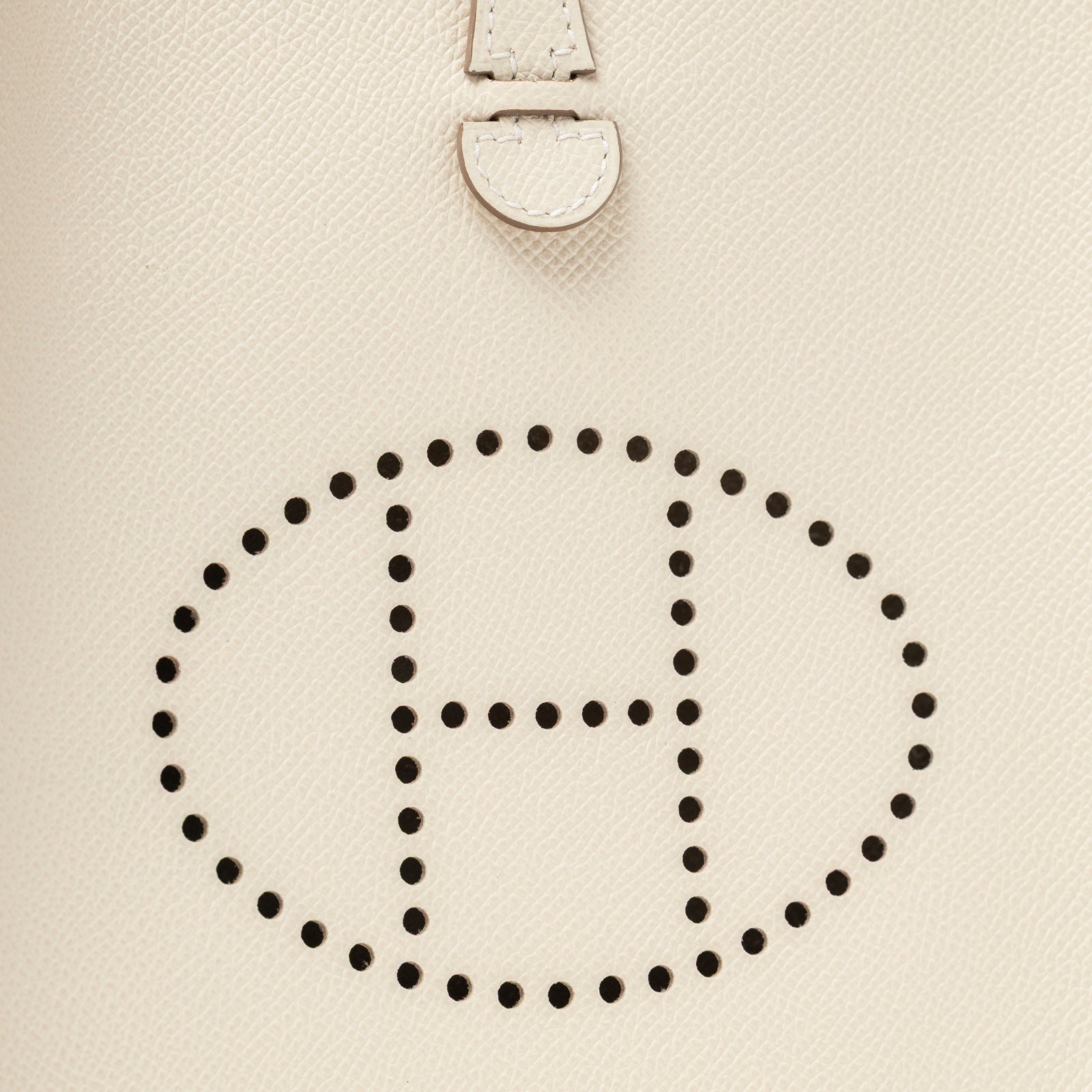 Close-up of perforated H logo on Hermès Mini Evelyne Sellier Craie Epsom Gold Hardware leather surface