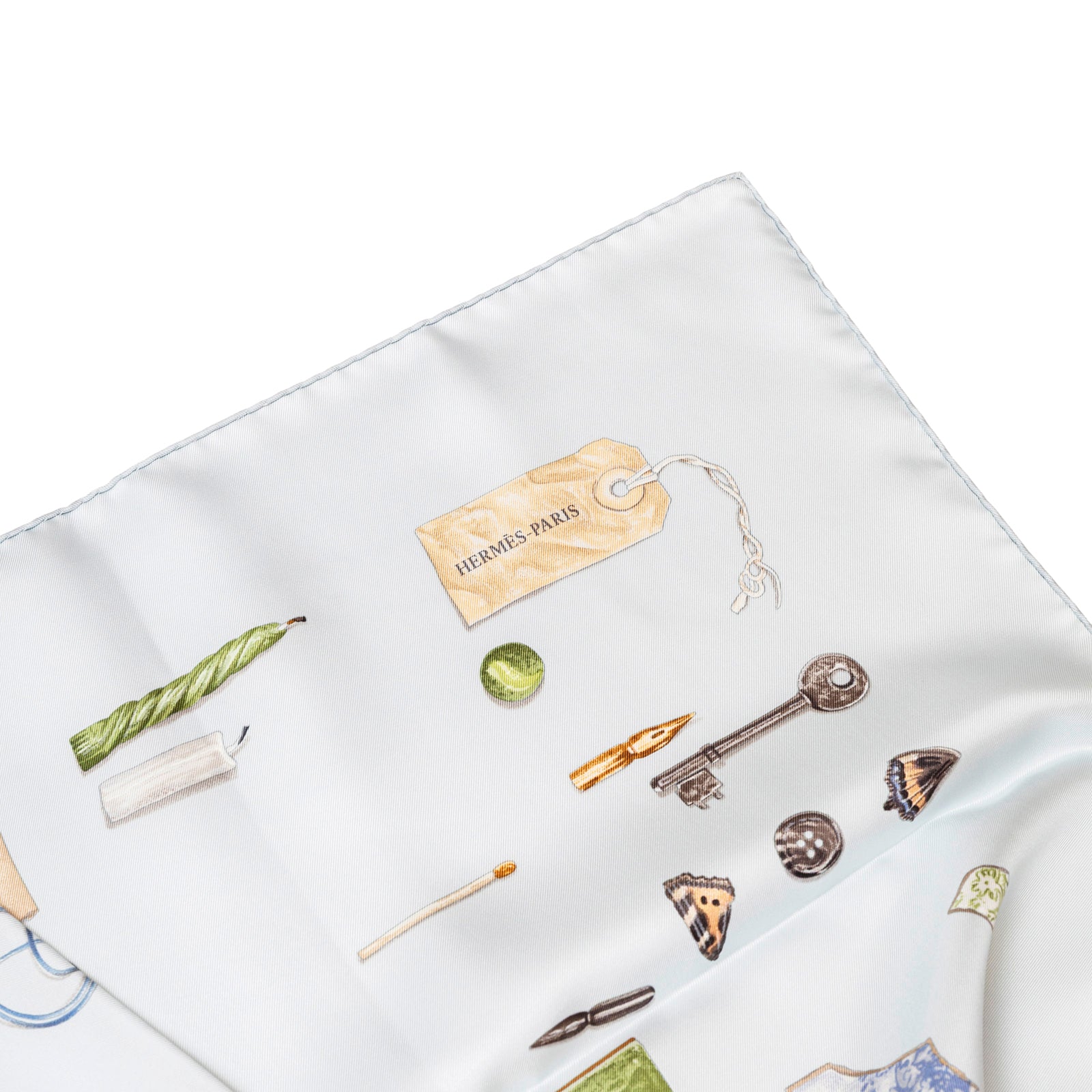 Top-down view of folded Hermès Carre Scarf 90 In The Pocket Blue Glacier/Blue Pale with illustrated details on white silk background