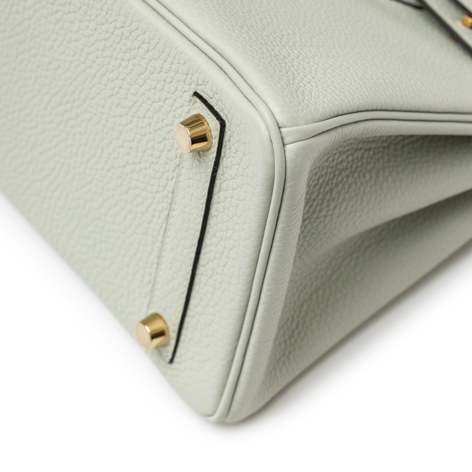 Close-up angled view of bottom corner and gold hardware feet on Hermès Birkin 25 Gris Neve Togo Gold Hardware