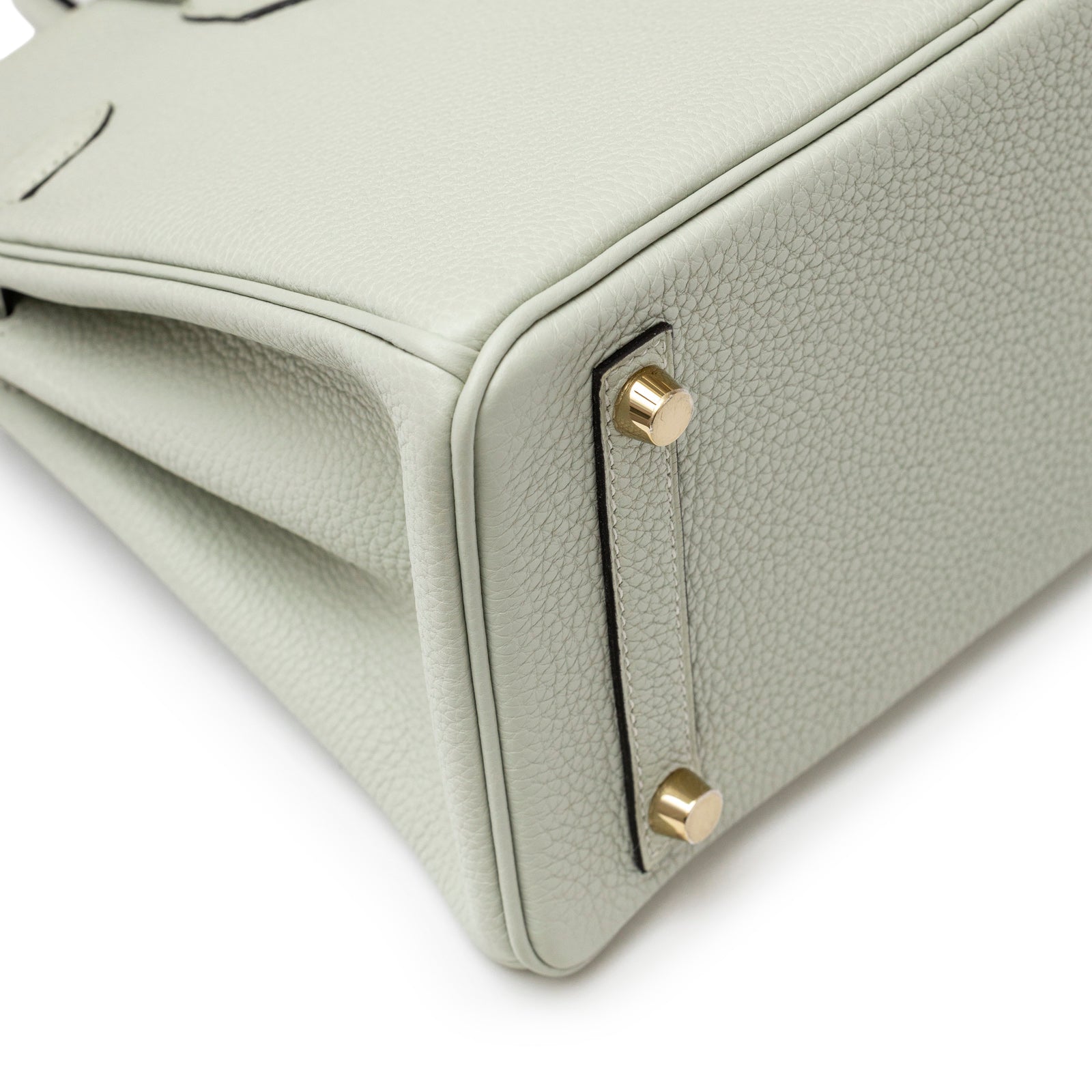 Close-up angled view of gold hardware feet on bottom corner of Hermès Birkin 25 Gris Neve Togo Gold Hardware bag