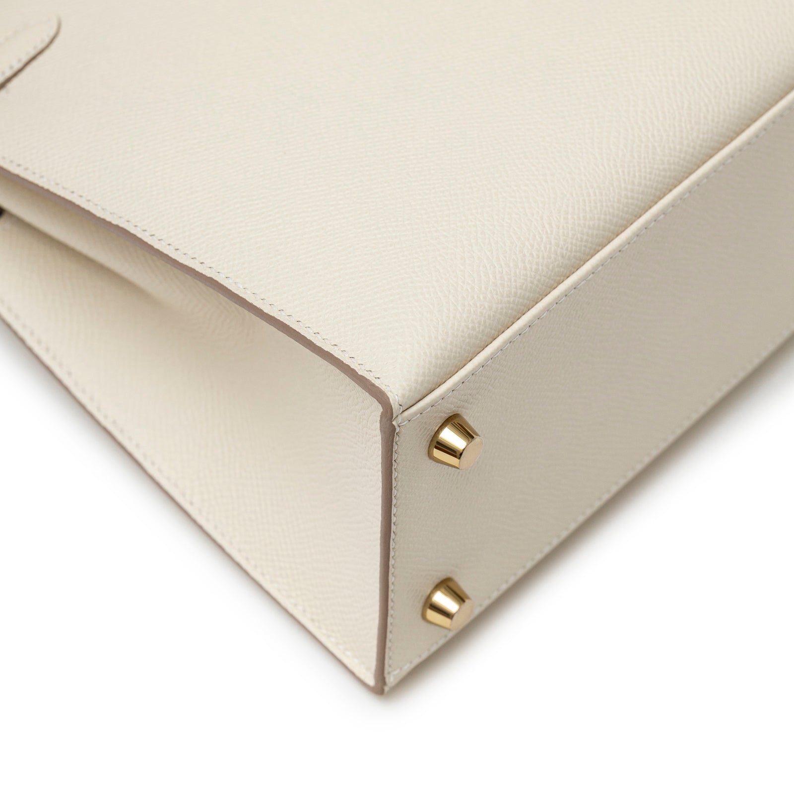 Close-up angled view of bottom corner with gold Permabrass feet on Hermès Kelly 25 Sellier Epsom Craie Permabrass Hardware handbag