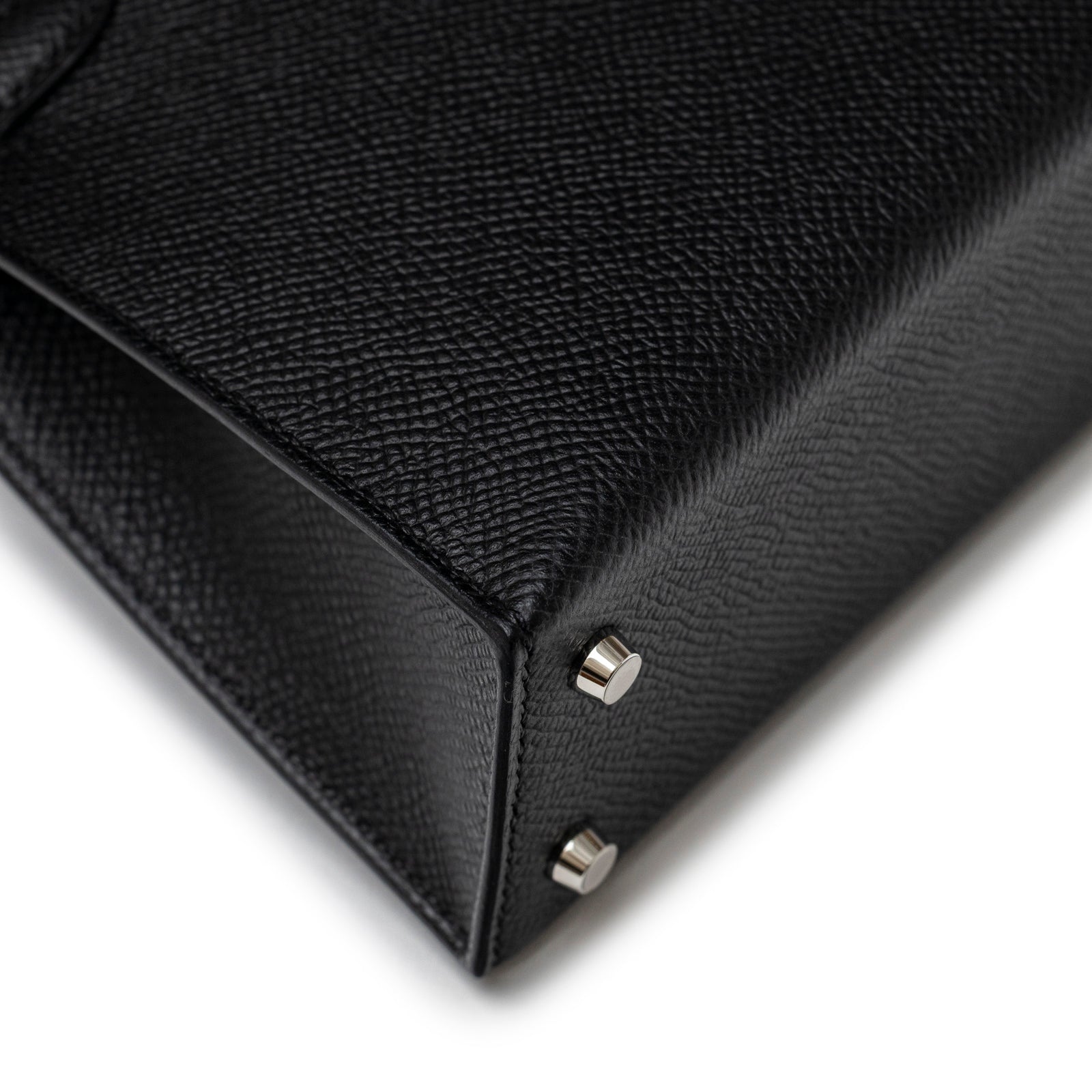 Close-up angled view of Hermès Mini Kelly II Sellier Black Epsom Palladium Hardware bag base with protective feet