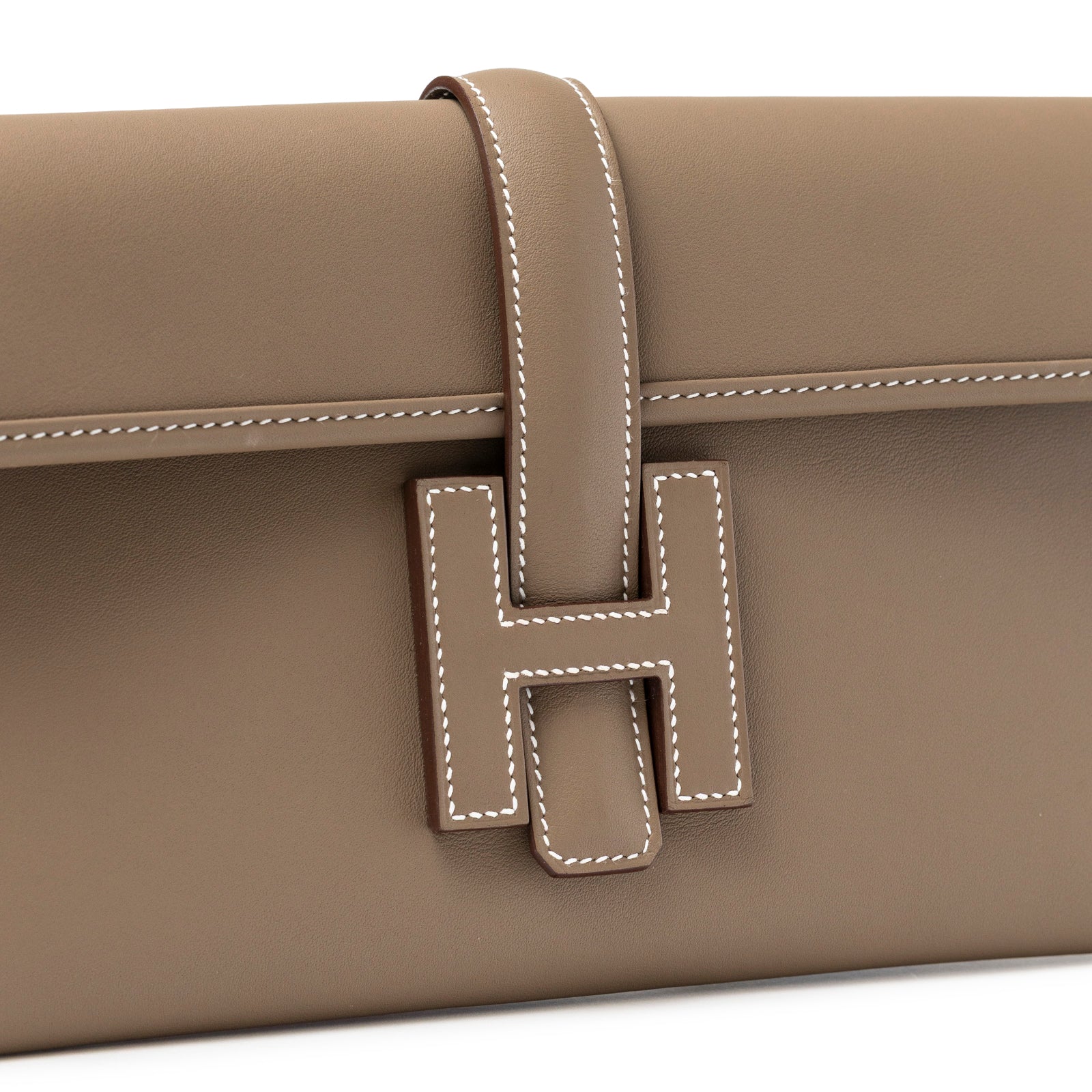 Close-up of Hermès Jige Elan 29 Clutch Etoupe Swift showing signature H clasp and detailed white stitching