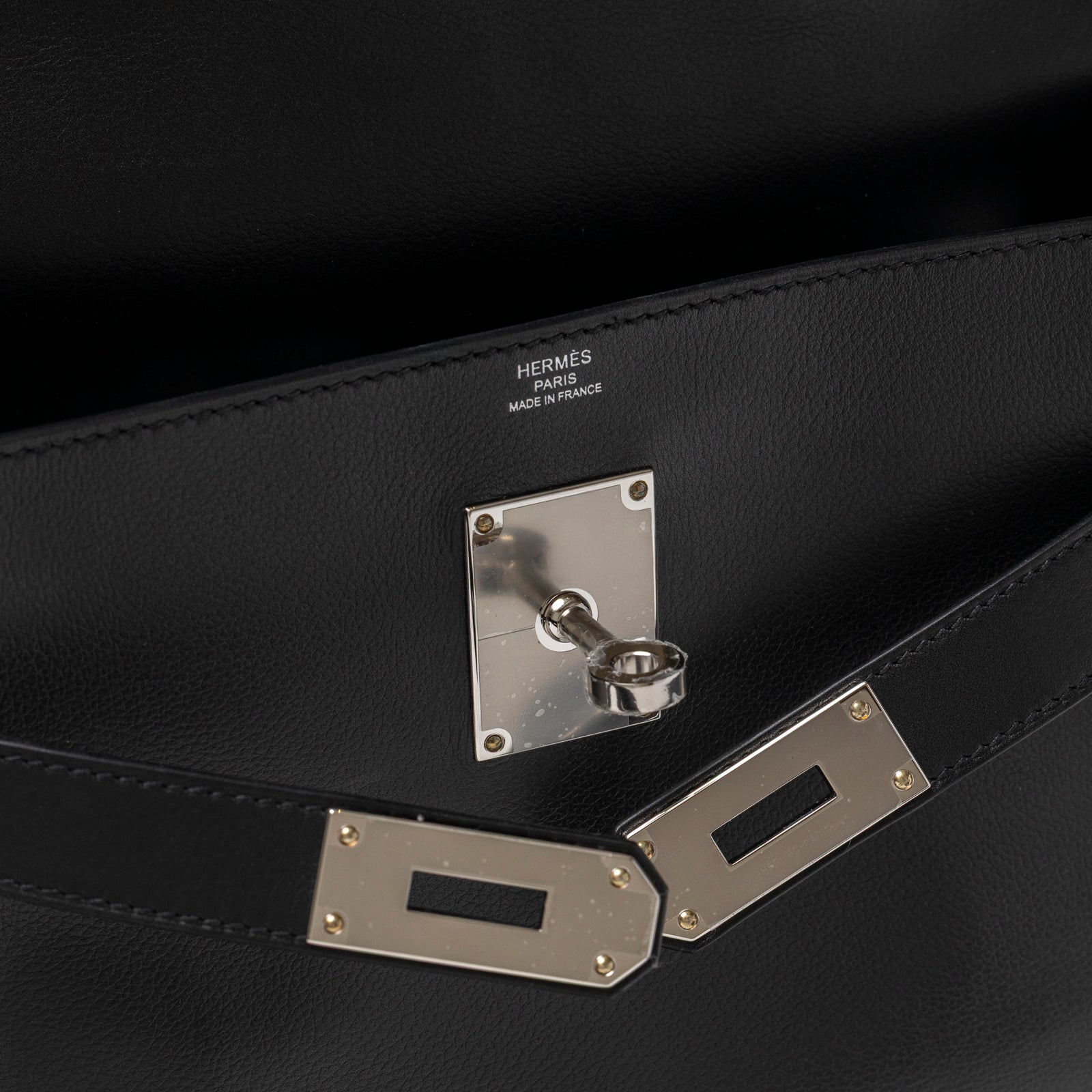 Close-up of Hermès Kelly Messenger PM Black Evergrain Palladium Hardware showing lock and interior stamp