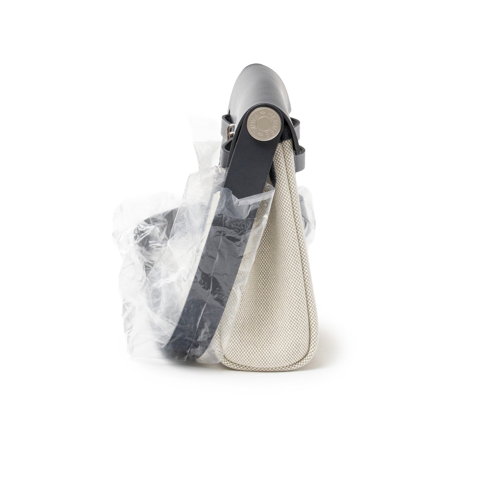 Side view of Hermès Mini Herbag Zip 20 Ecru-Blue Glacier/Ardoise Toile and Vache Hunter Palladium Hardware with strap wrapped in plastic