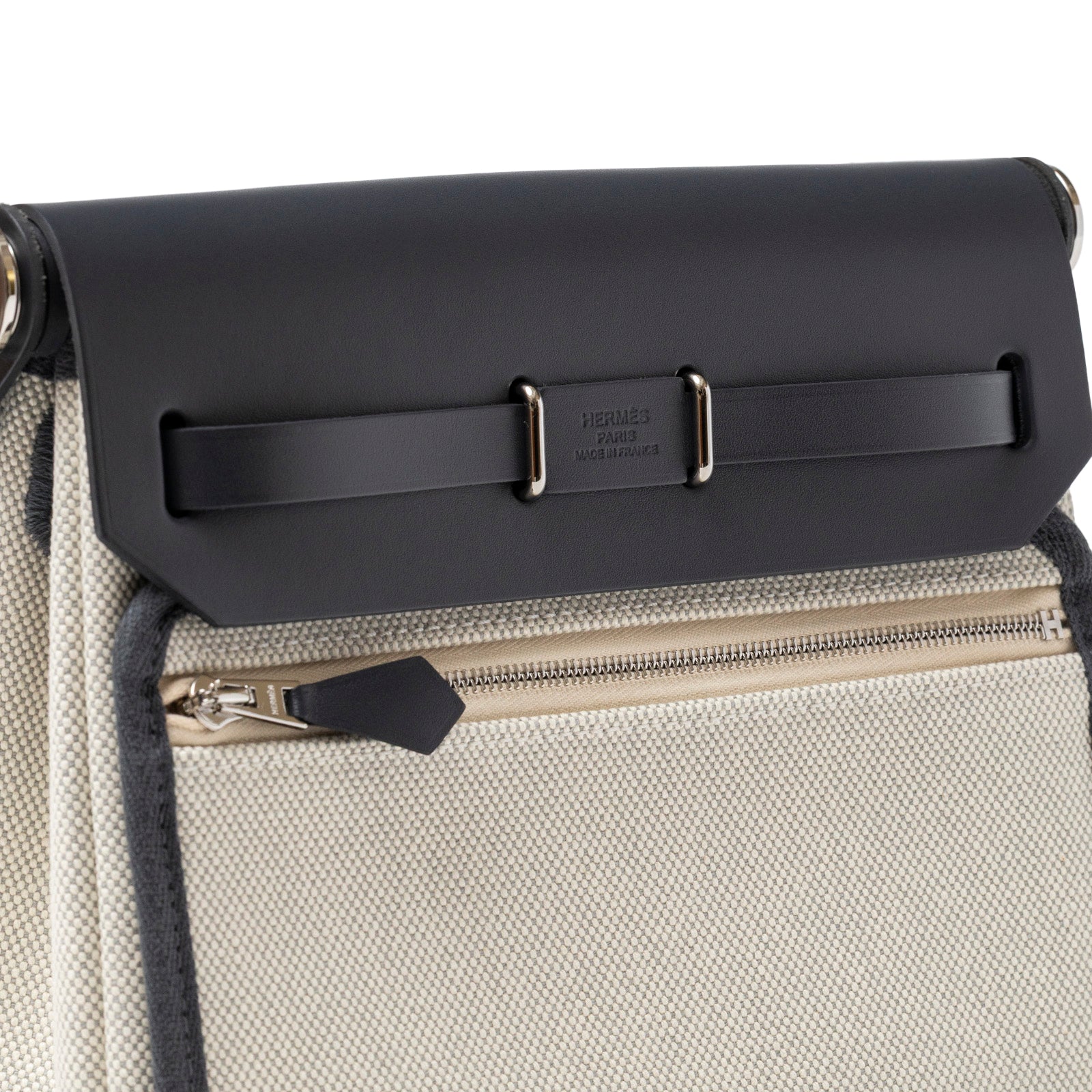 Close-up angled view of Hermès Mini Herbag Zip 20 Ecru-Blue Glacier/Ardoise Toile and Vache Hunter Palladium Hardware showing zip pocket and leather flap