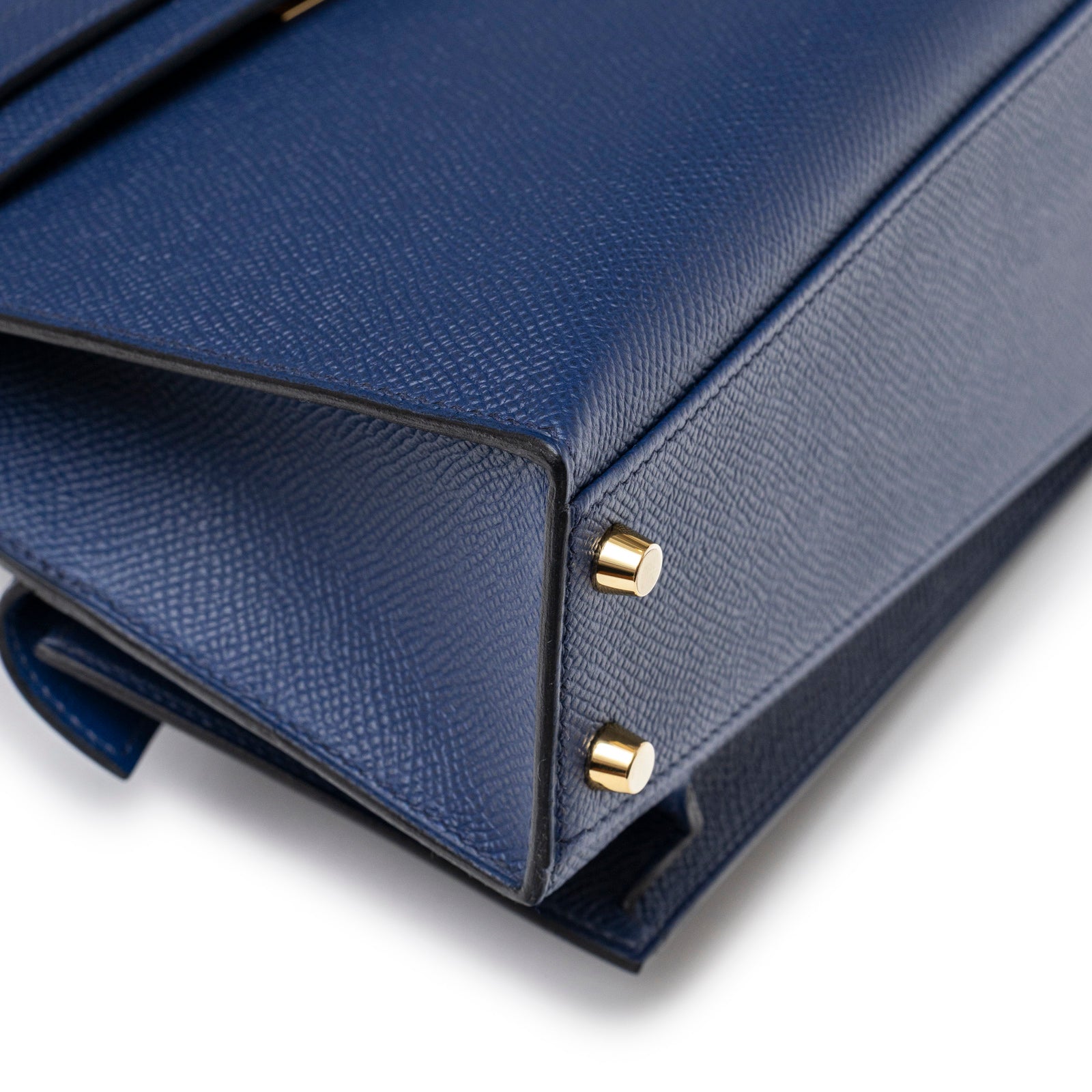 Close-up angled shot of Hermès Kelly Desordre 20 Sellier Blue Saphir Epsom Gold Hardware corner detailing and base studs