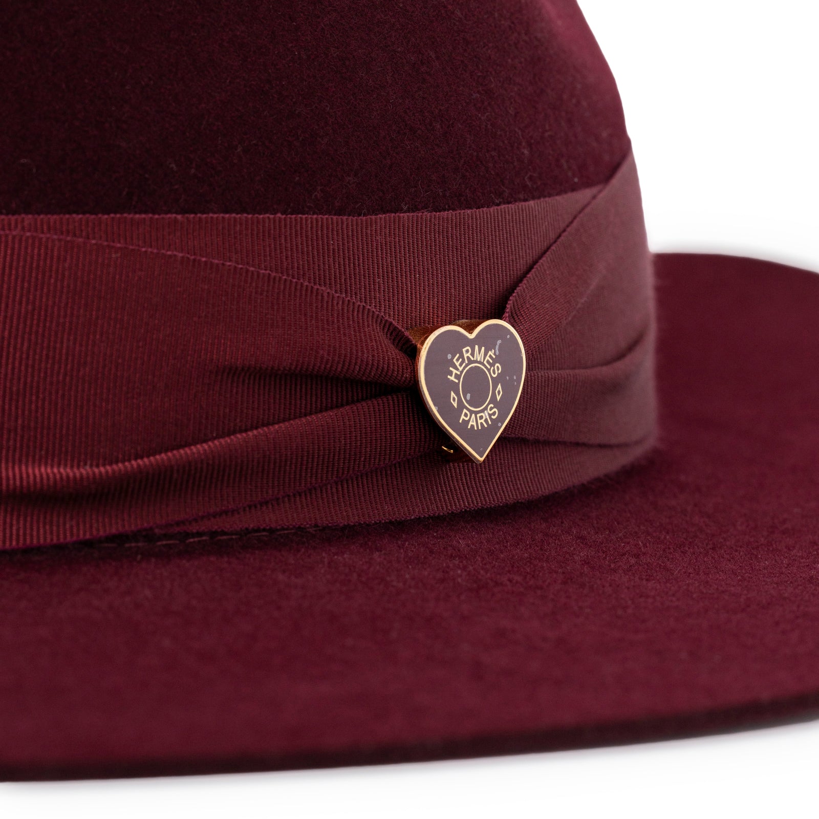 Close-up of Hermès Felt Hat Red Lacquered Brass Heart showing burgundy felt and heart-shaped brass detail