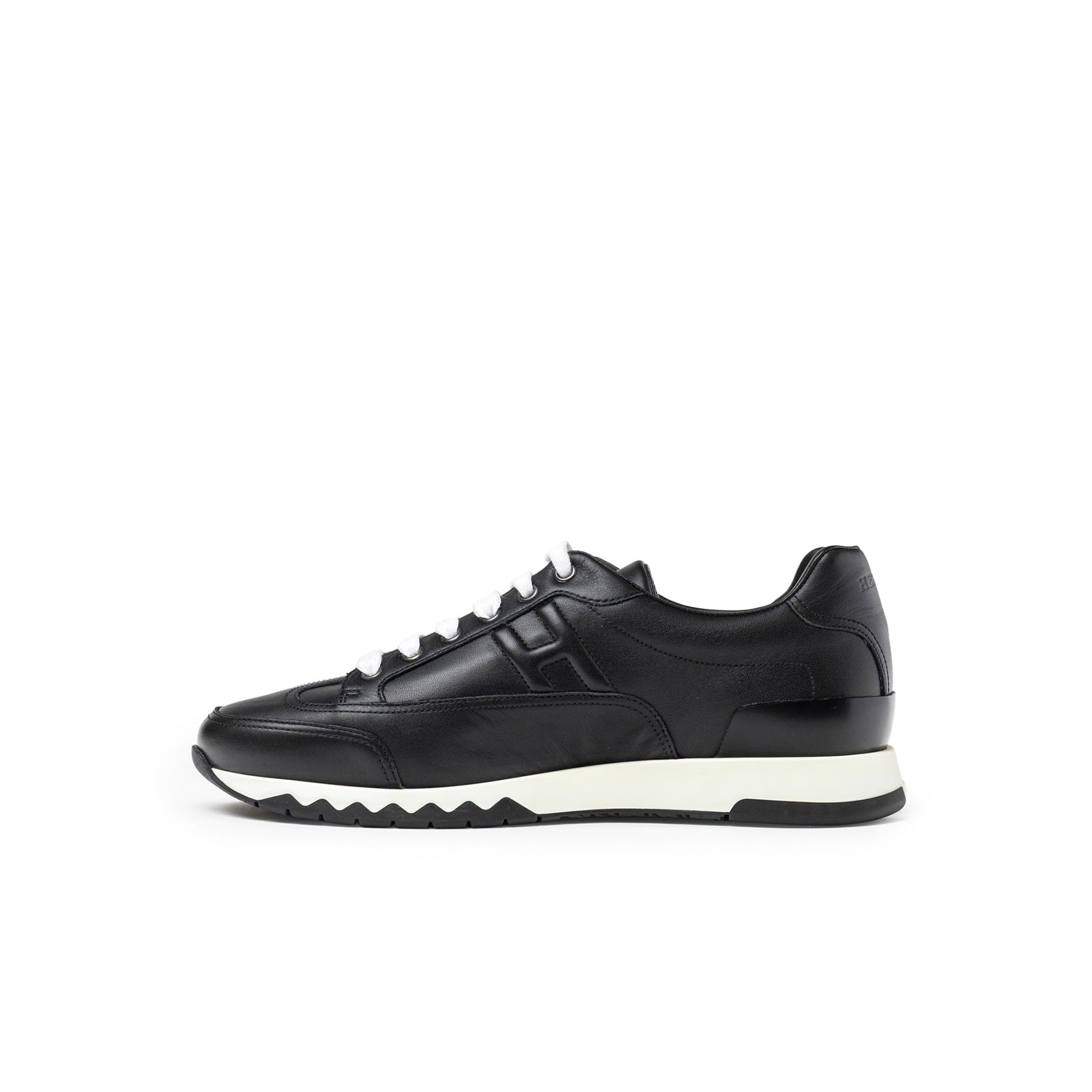 Side view of Hermès Men's Trail Sneaker Black in smooth leather with white laces and a contrasting sole