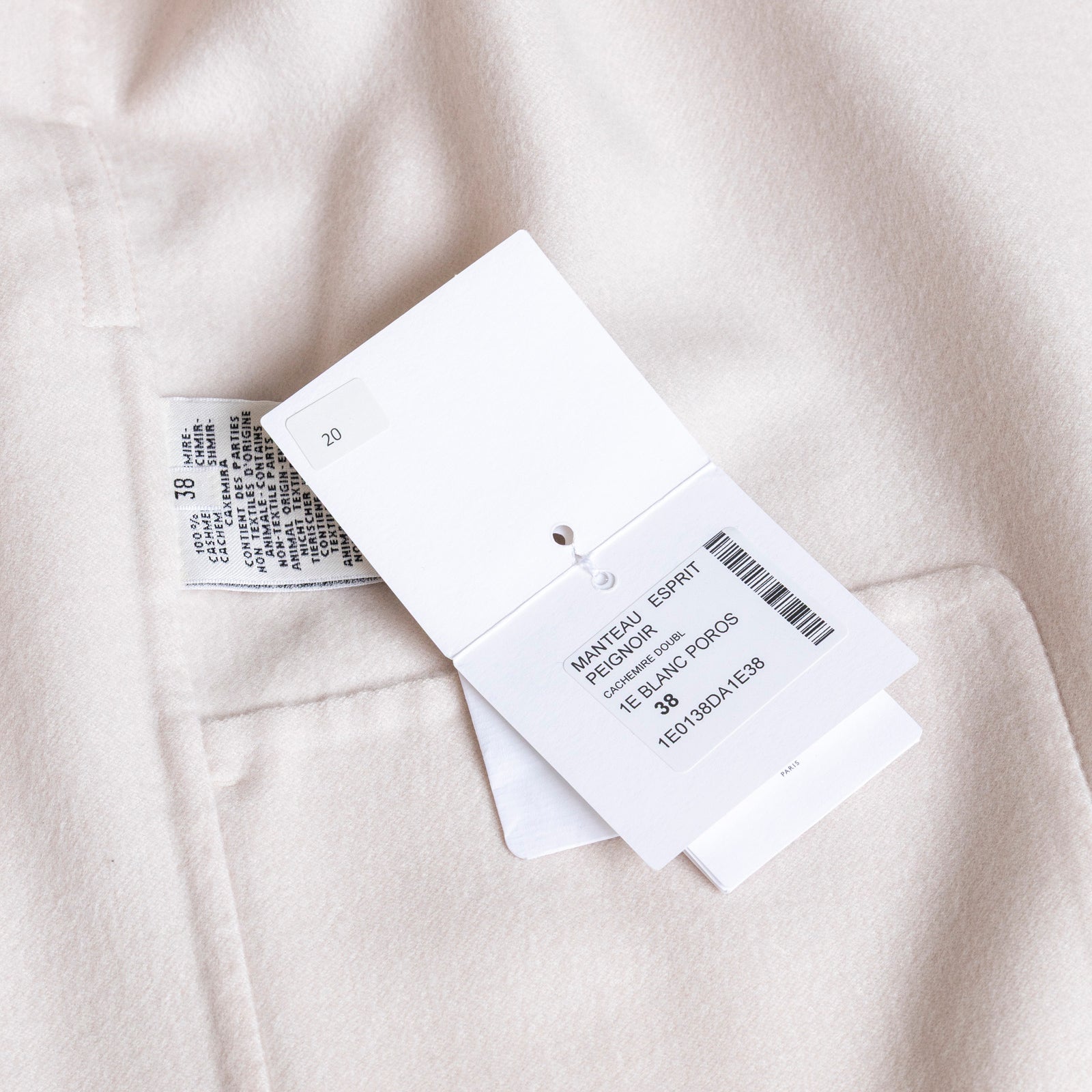 Close-up of Hermès Manteau Esprit Peignoir Cashmere Doubleface Coat label and size tag FR 38 on cream fabric