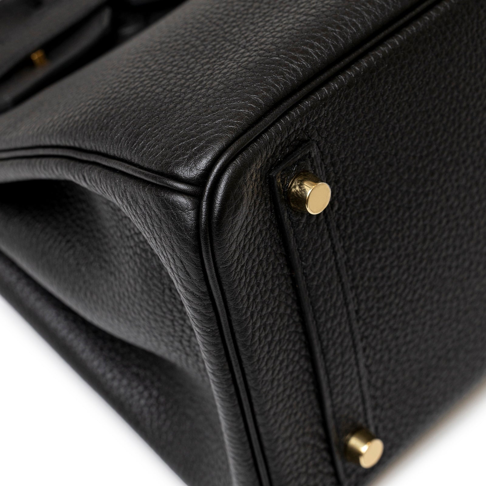 Close-up of textured black leather corner and gold hardware feet on Hermès Birkin 30 Black Togo Gold Hardware handbag.