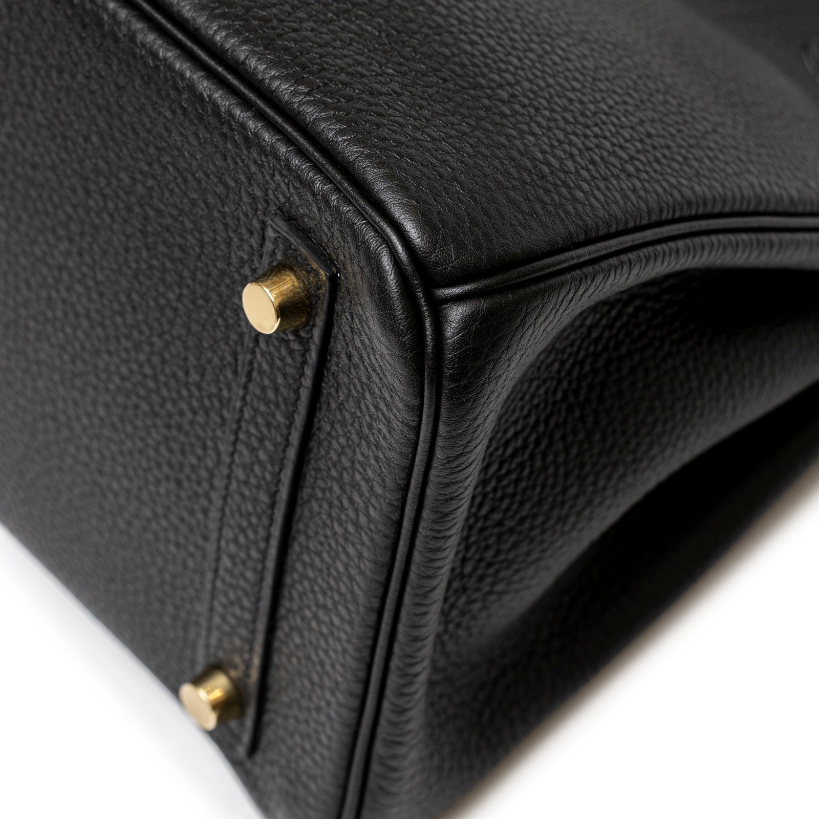 Close-up of Hermès Birkin 30 Black Togo Gold Hardware corner showcasing textured leather and polished gold metal feet detailing