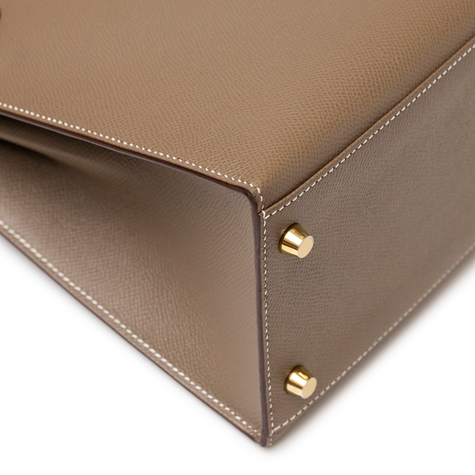 Close-up of bottom corner showing gold hardware feet and detailed stitching of Hermès Kelly 28 Sellier Etoupe Epsom Gold hardware