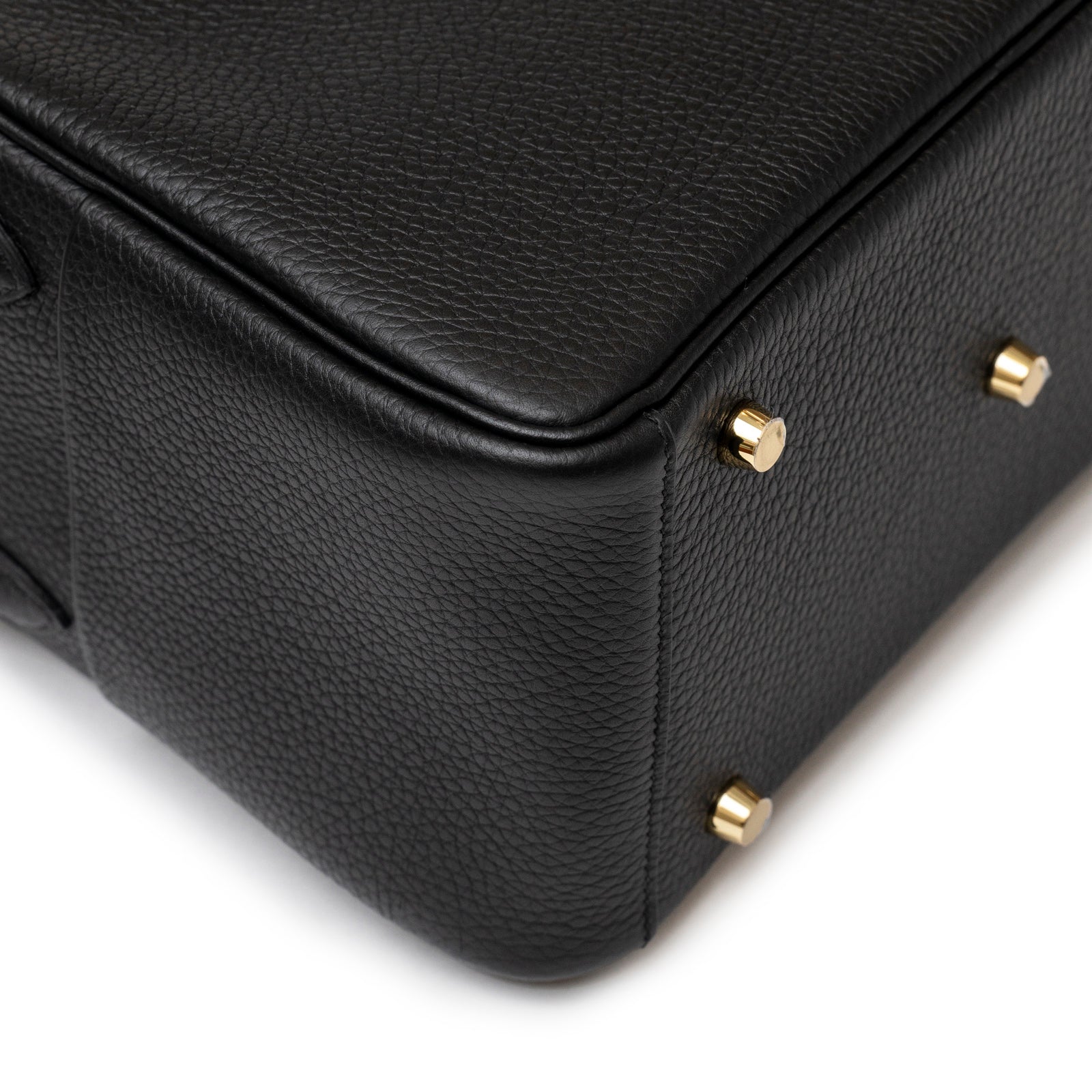 Close-up of the bottom corner of the Hermès Lindy 26 Black Clemence Gold Hardware showing textured leather and gold metal studs details.