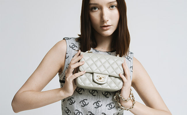 A woman elegantly holds a Chanel purse in front of her, showcasing its luxury design and style.