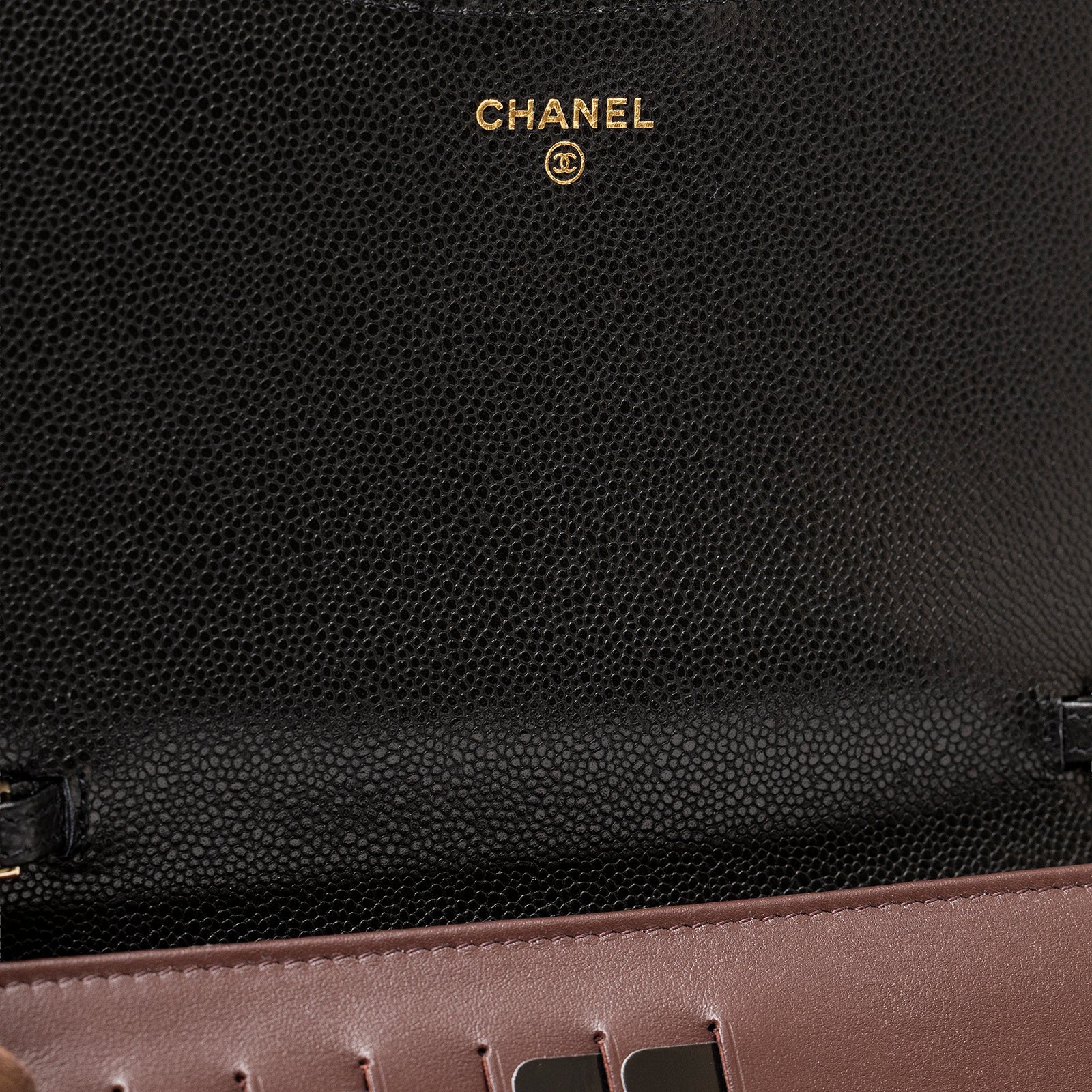 Close-up inside view of Chanel 24S Classic Clutch On Chain Caviar Black Gold Hardware showing logo embossing and stitching detail