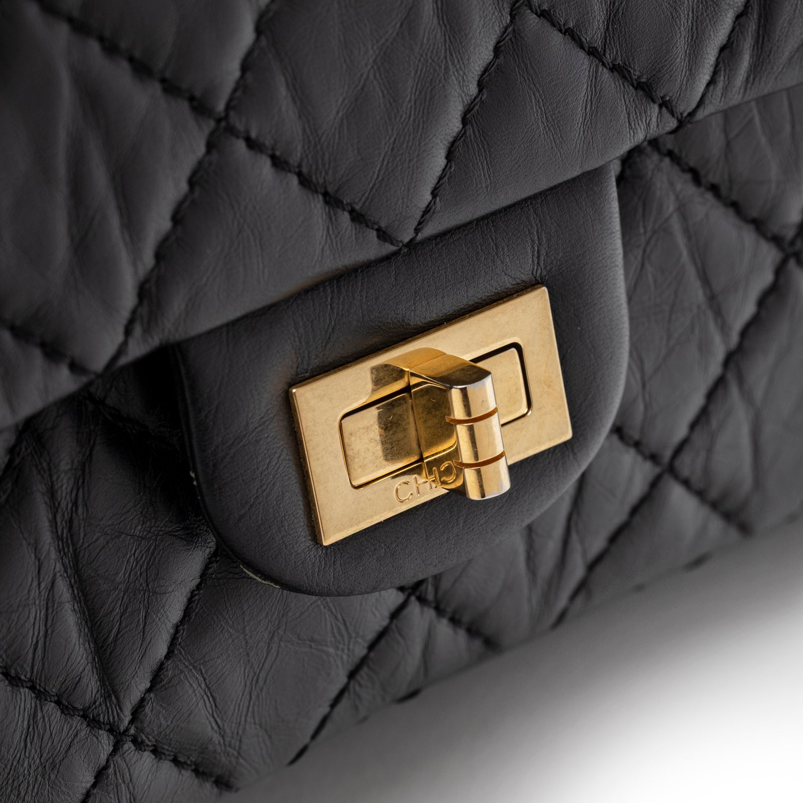 Close-up of the brushed gold hardware clasp on the Chanel 2.55 Reissue 226 Flap Black Aged Calfskin Brushed Gold Hardware handbag
