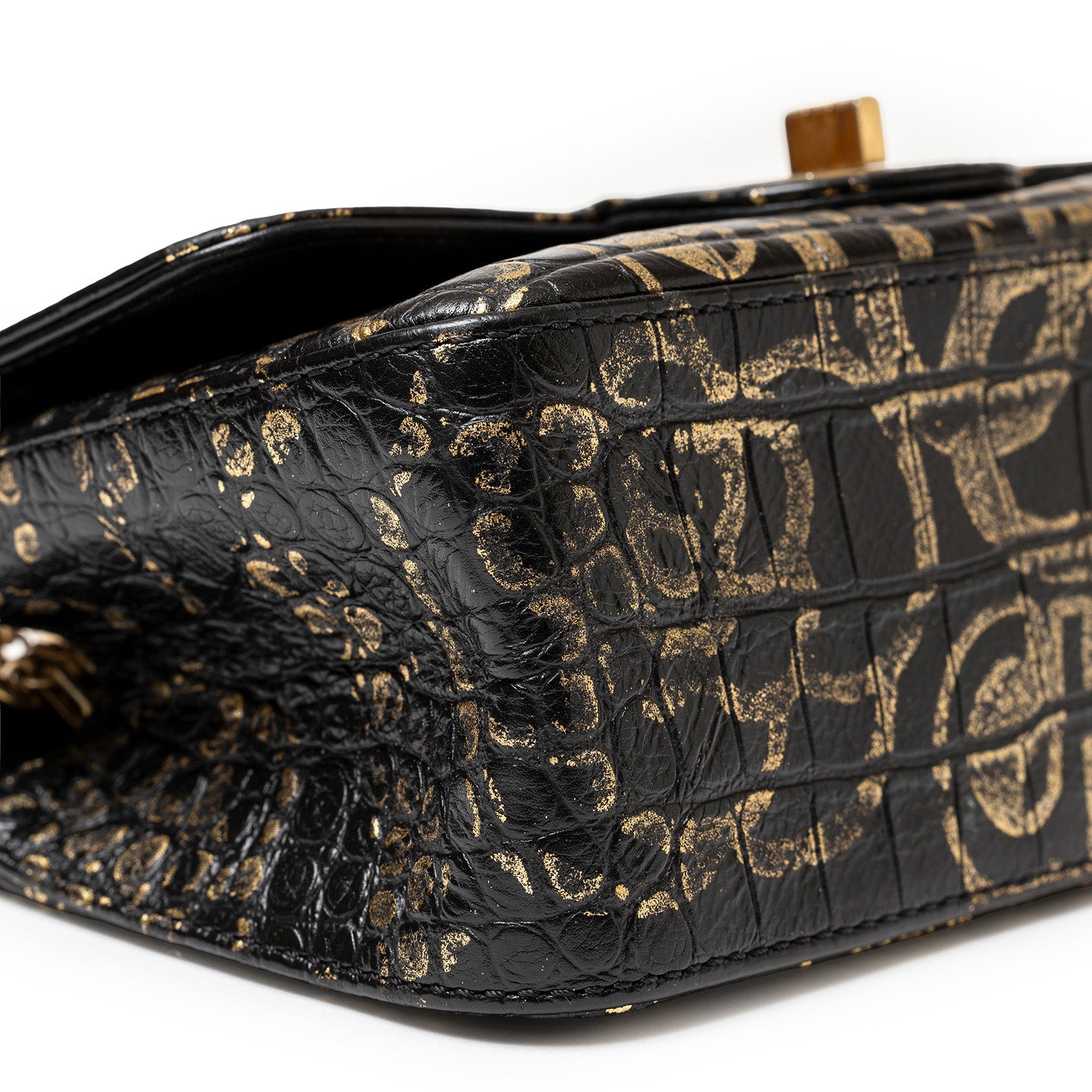 Close-up side view of Chanel 2.55 Reissue 224 Flap Bag Black and Gold Graffiti Crocodile Embossed Calfskin Gold Hardware showing texture and graffiti pattern