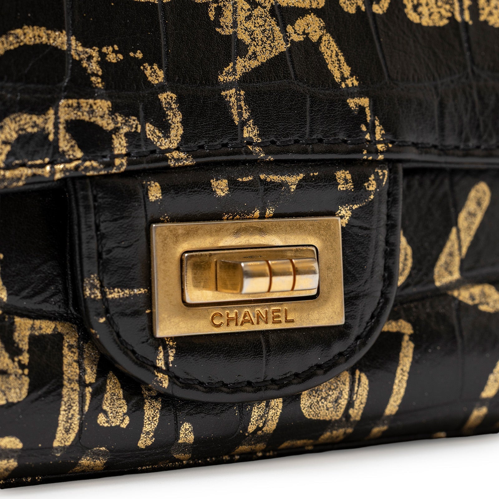 Close-up of gold hardware clasp on Chanel 2.55 Reissue 224 Flap Bag Black and Gold Graffiti Crocodile Embossed Calfskin