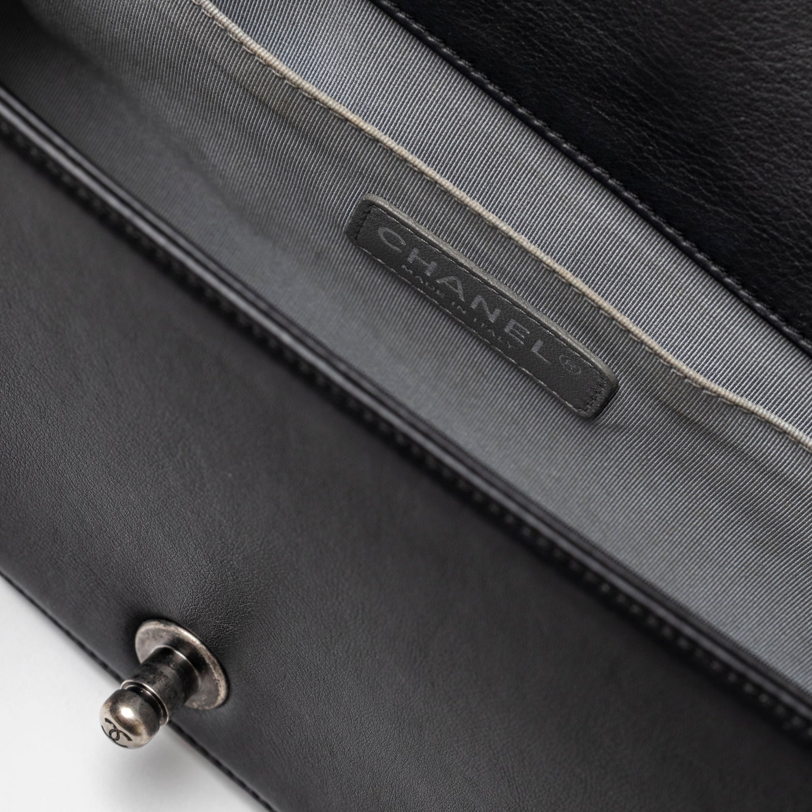 Close-up of interior label and fabric lining inside Chanel Boy Bag Medium Black Lambskin Ruthenium Hardware