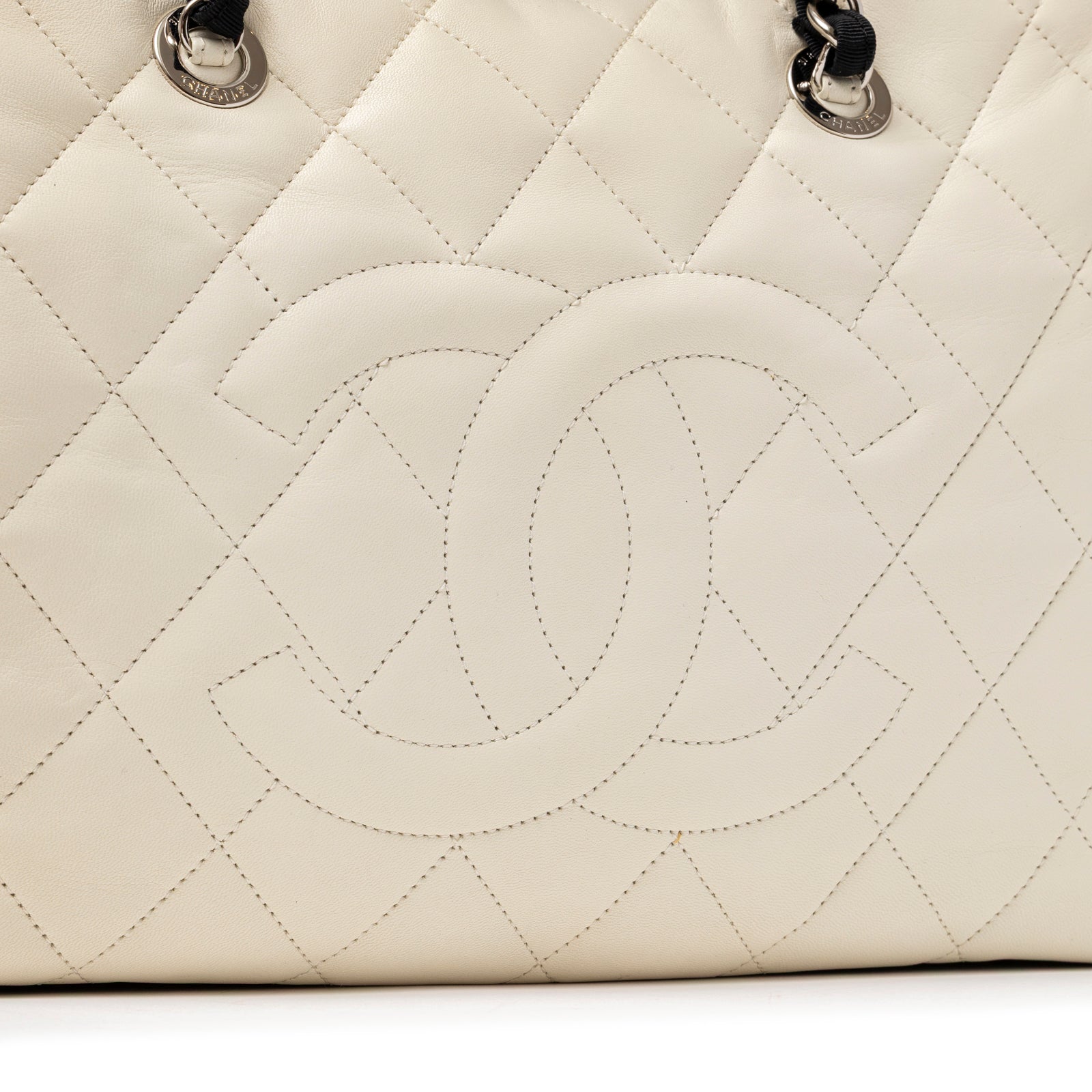 Close-up of quilted white lambskin leather with embossed Chanel CC logo on the Chanel CC Quilted Zip Shoulder Bag White & Black Lambskin Palladium Hardware