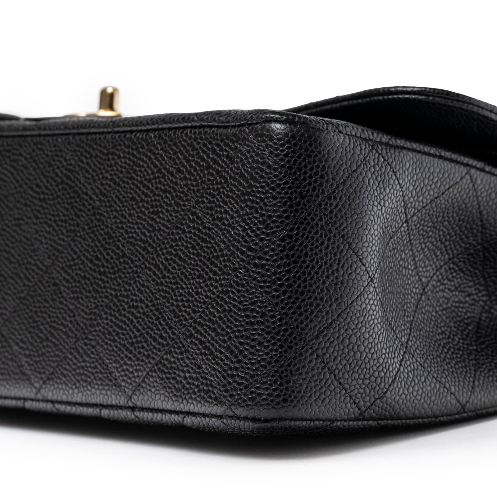 Close-up angled view of bottom corner showing caviar leather texture on Chanel Classic Flap Jumbo Caviar Black Gold Hardware