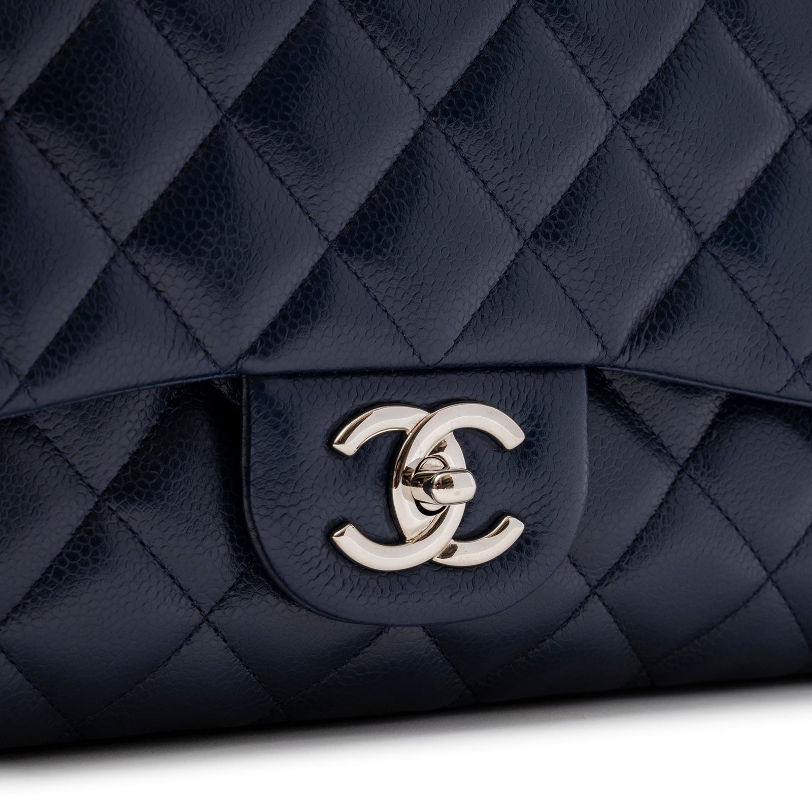 Close-up of clasp and quilted caviar leather on Chanel Maxi Classic Double Flap Caviar Navy Palladium Hardware bag