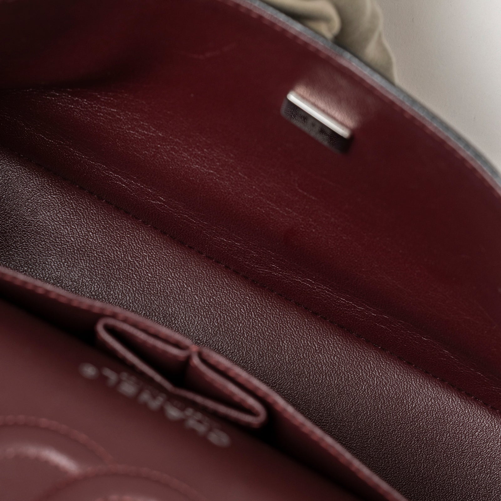 Close-up inside view of burgundy leather interior pocket with embossed logo on Chanel Medium Classic Flap Bag Black Caviar Palladium Hardware