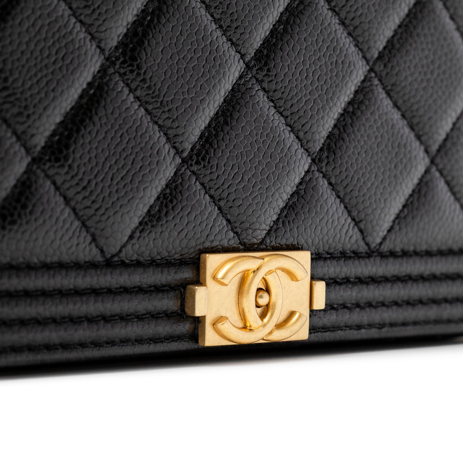 Close-up of brushed gold logo clasp on quilted black caviar leather Chanel Mini Boy Wallet on Chain Black Caviar Brushed Gold Hardware