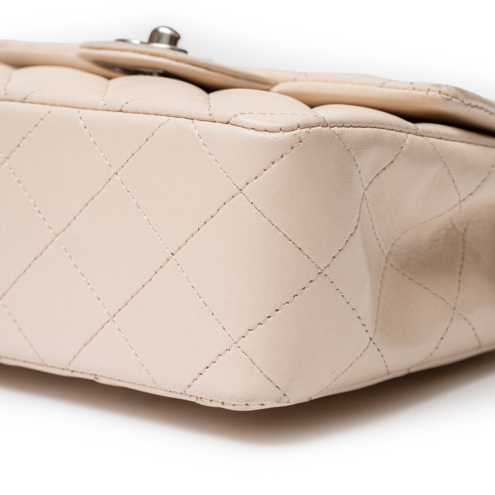 Close-up angled shot of beige Chanel Mini Square Single Flap Lambskin Beige Silver Hardware stitching detail and corner