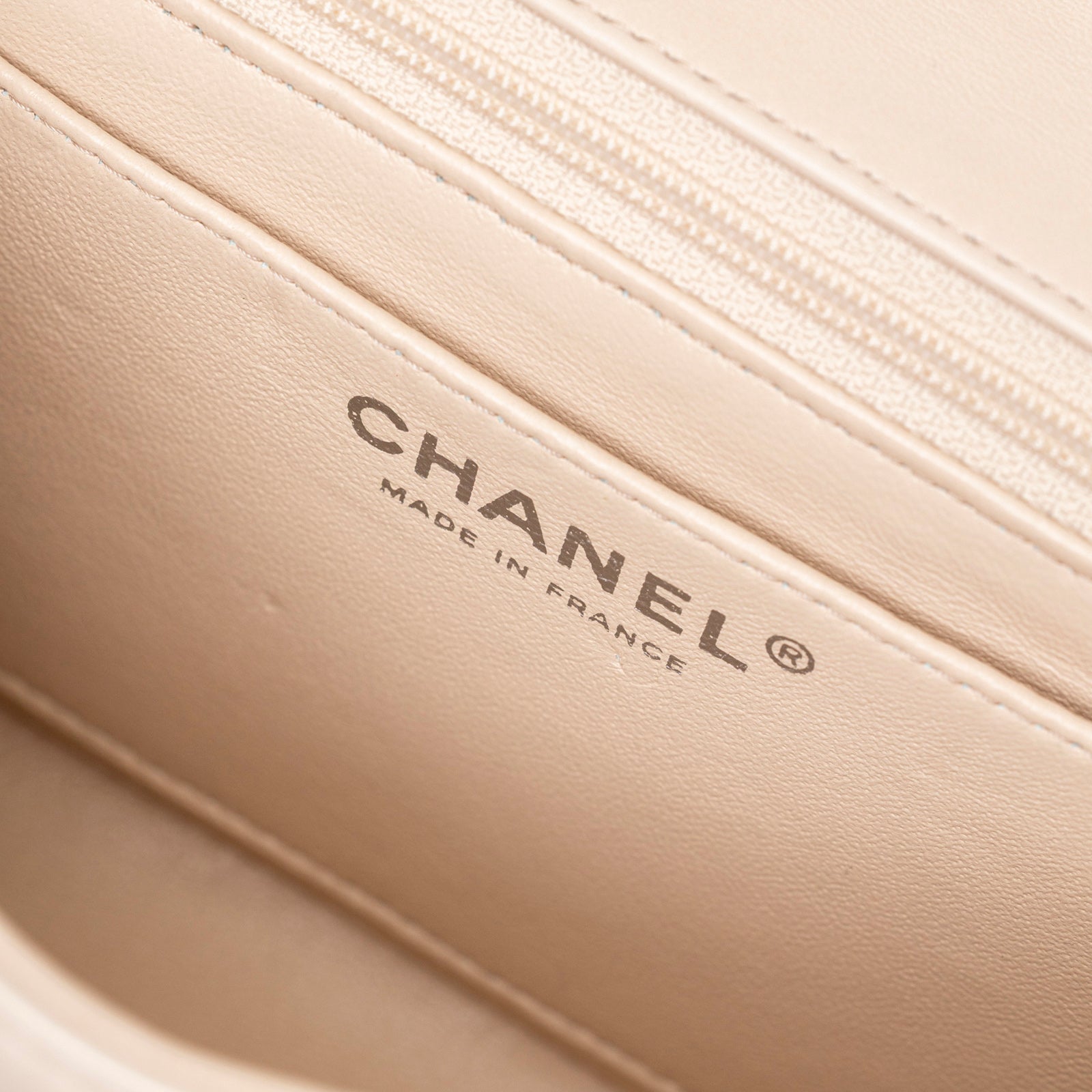 Close-up interior view of Chanel Mini Square Single Flap Lambskin Beige Silver Hardware showing logo and stitching detail